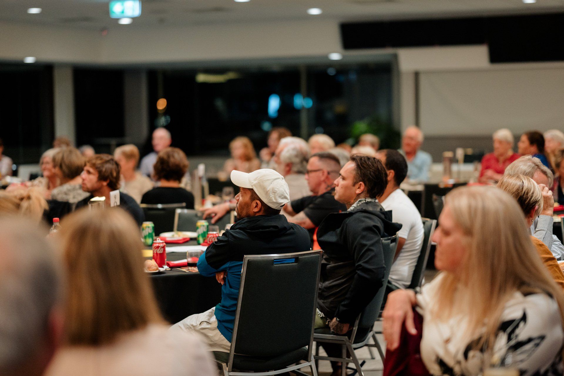 A large group of people are sitting at tables in a room.