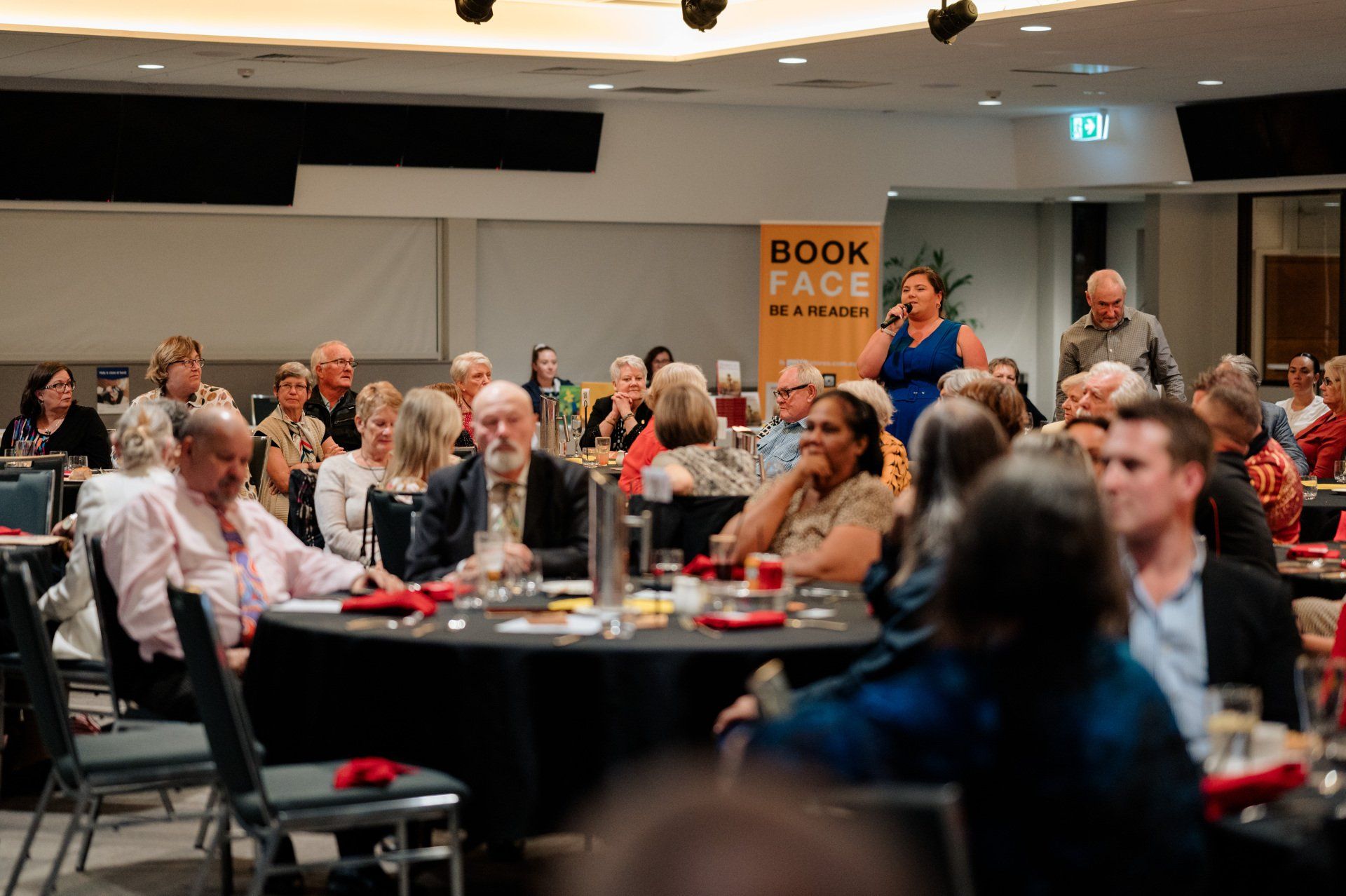 A large group of people are sitting at tables in a room.