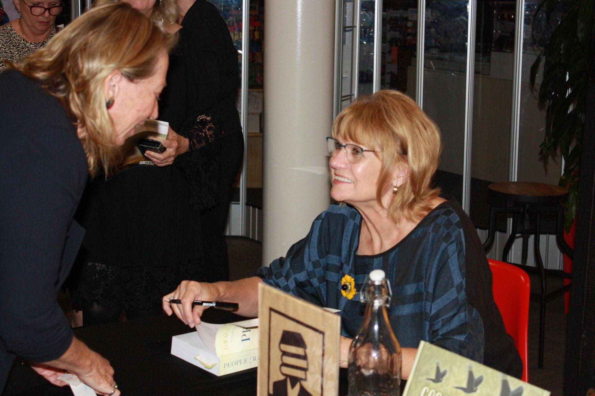 Two women are sitting at a table with a sign that says ' ed ' on it
