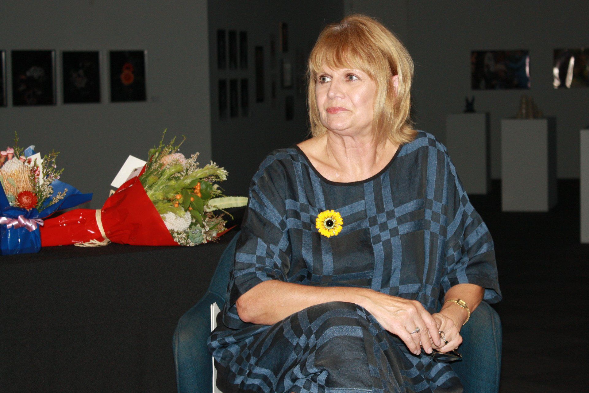 A woman is sitting in a chair in front of a bouquet of flowers.