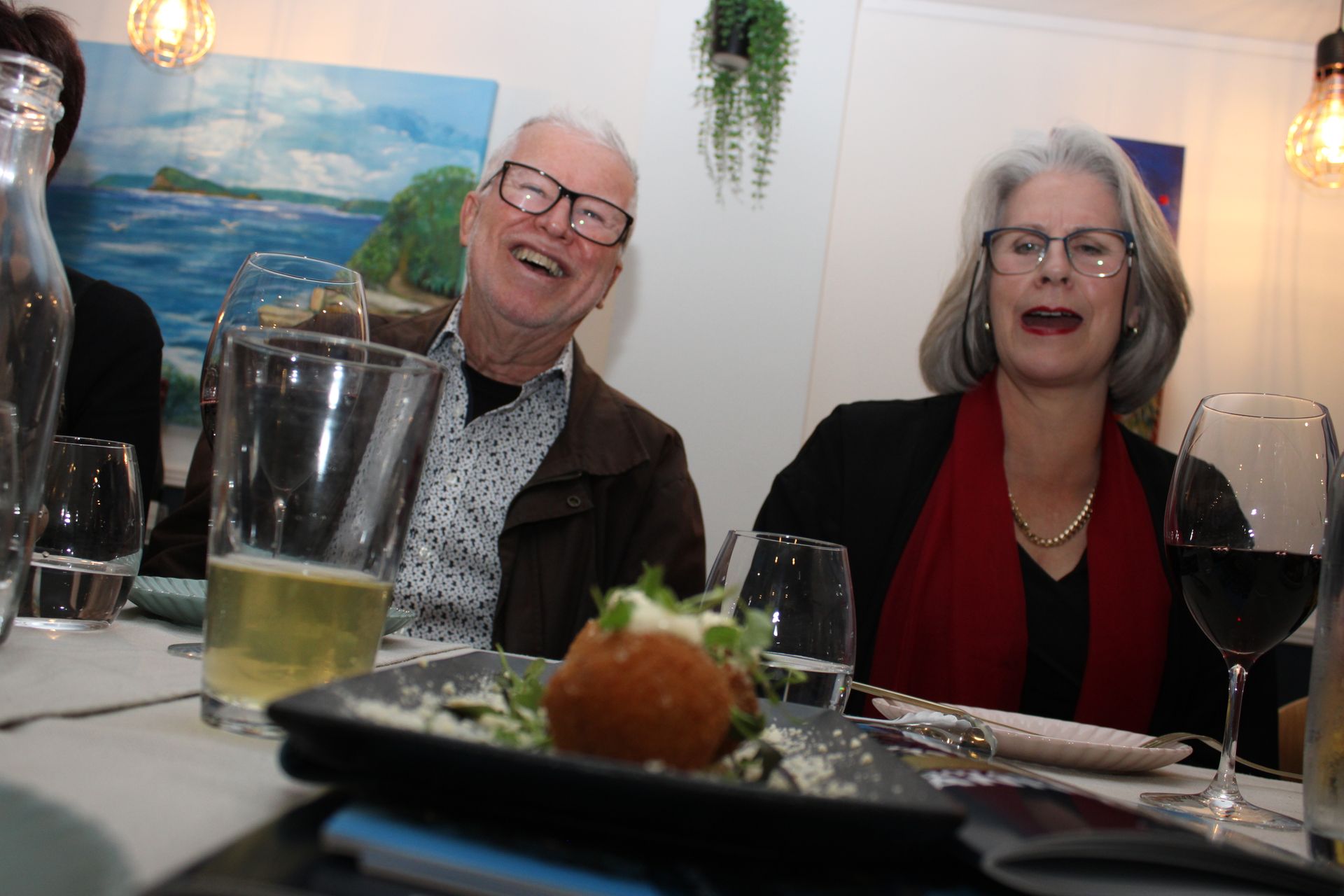A man and a woman are sitting at a table with glasses of wine.