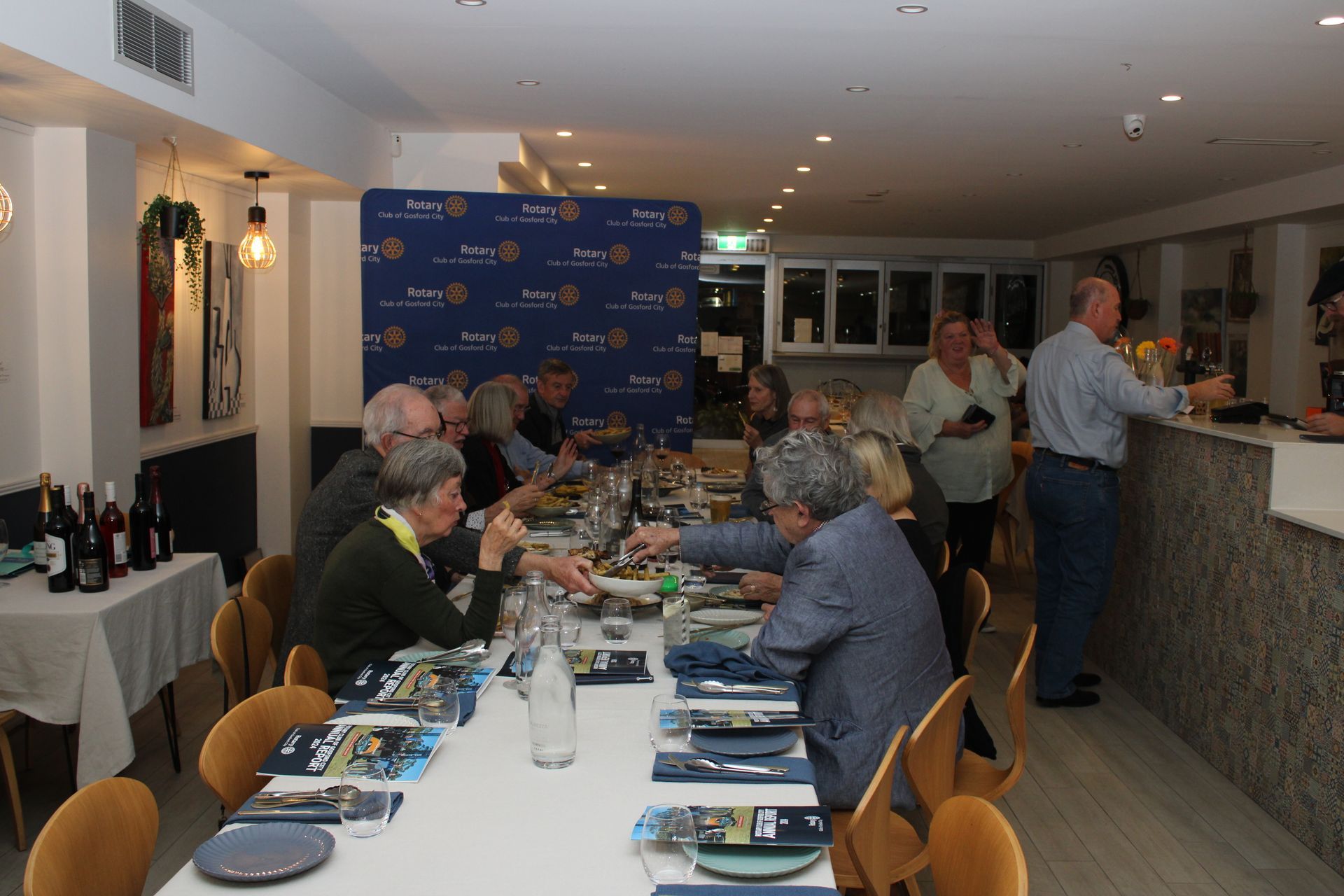 A group of people are sitting at a long table in a restaurant