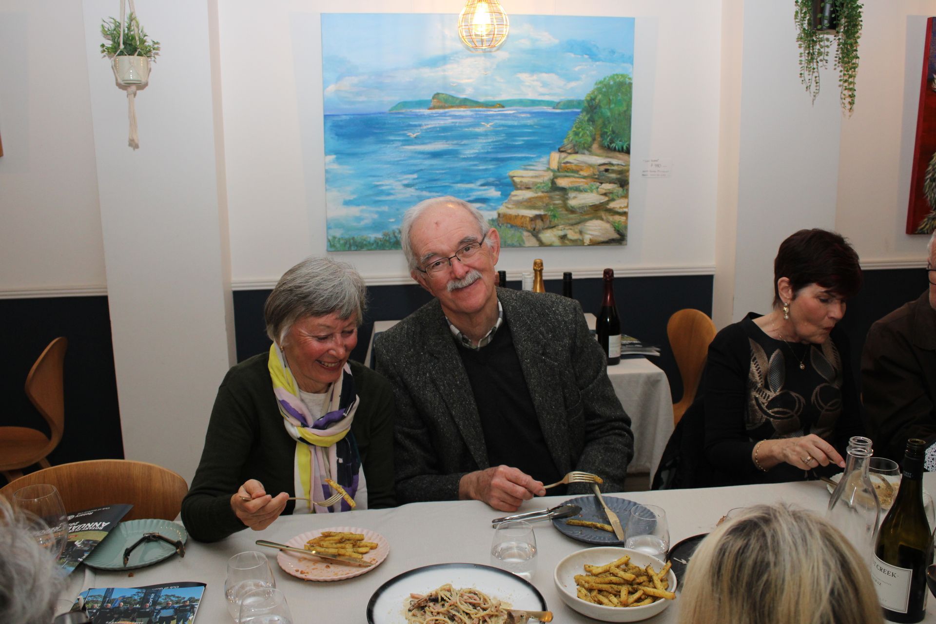 A man and a woman are sitting at a table with plates of food.