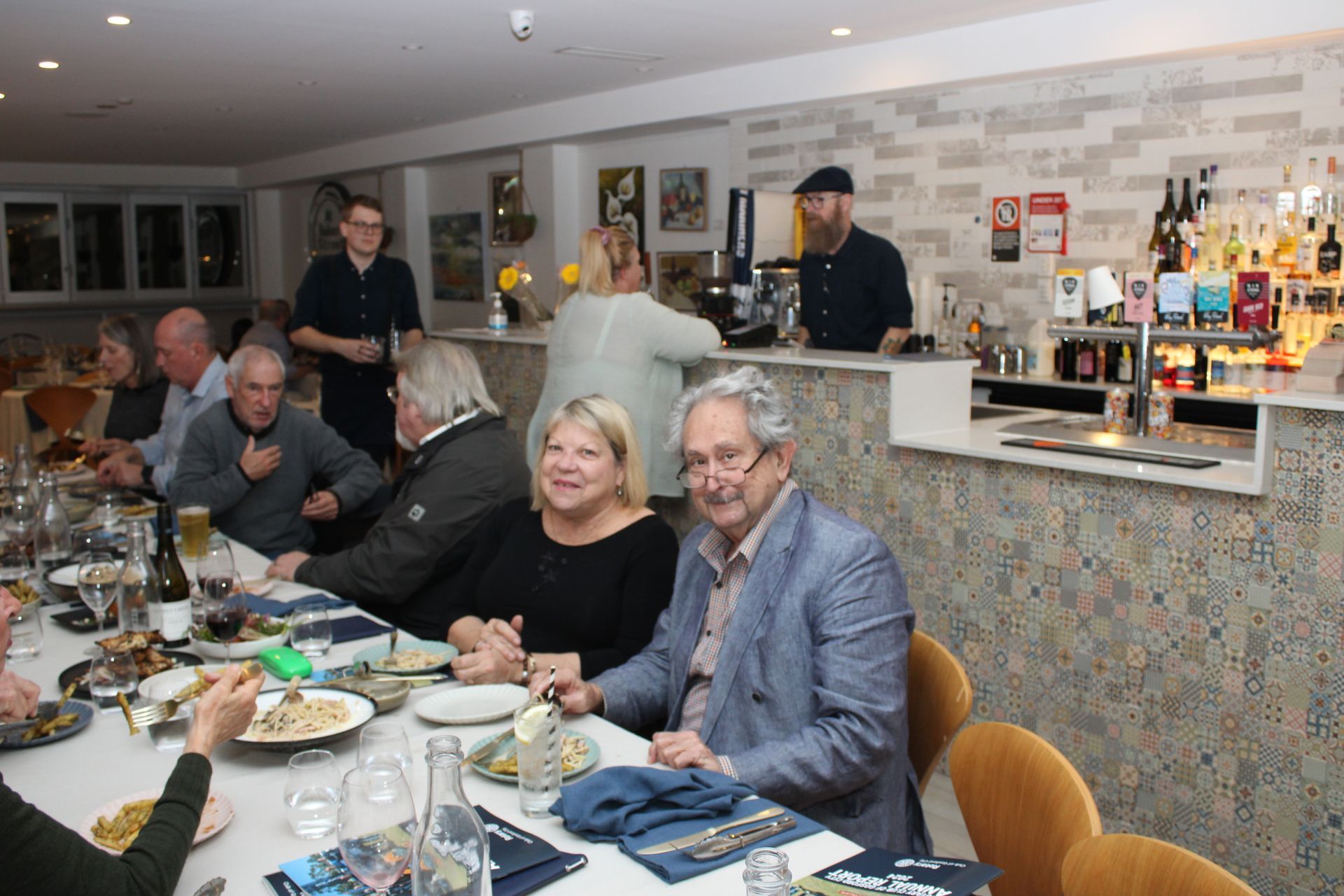 A group of people are sitting at a long table in a restaurant.