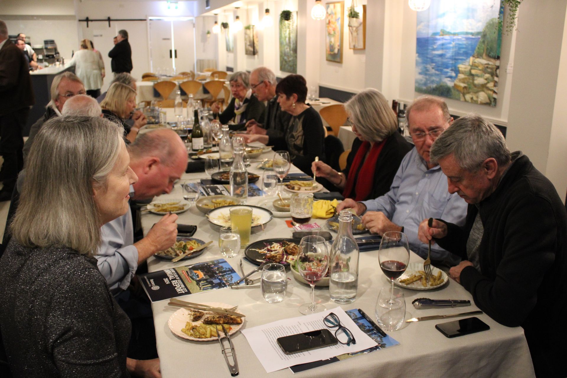 A group of people are sitting at a long table eating food.