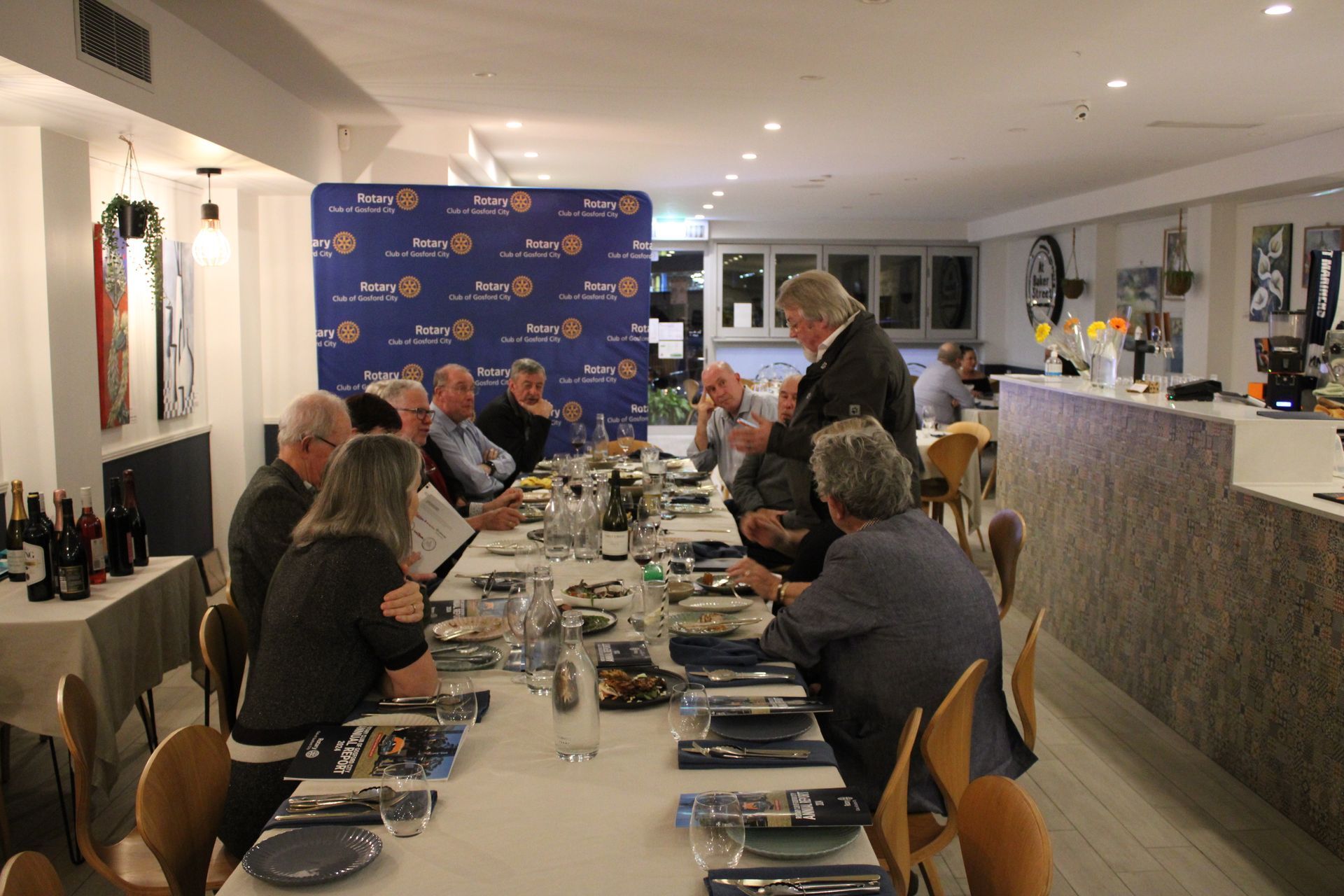 A group of people are sitting at a long table in a restaurant.