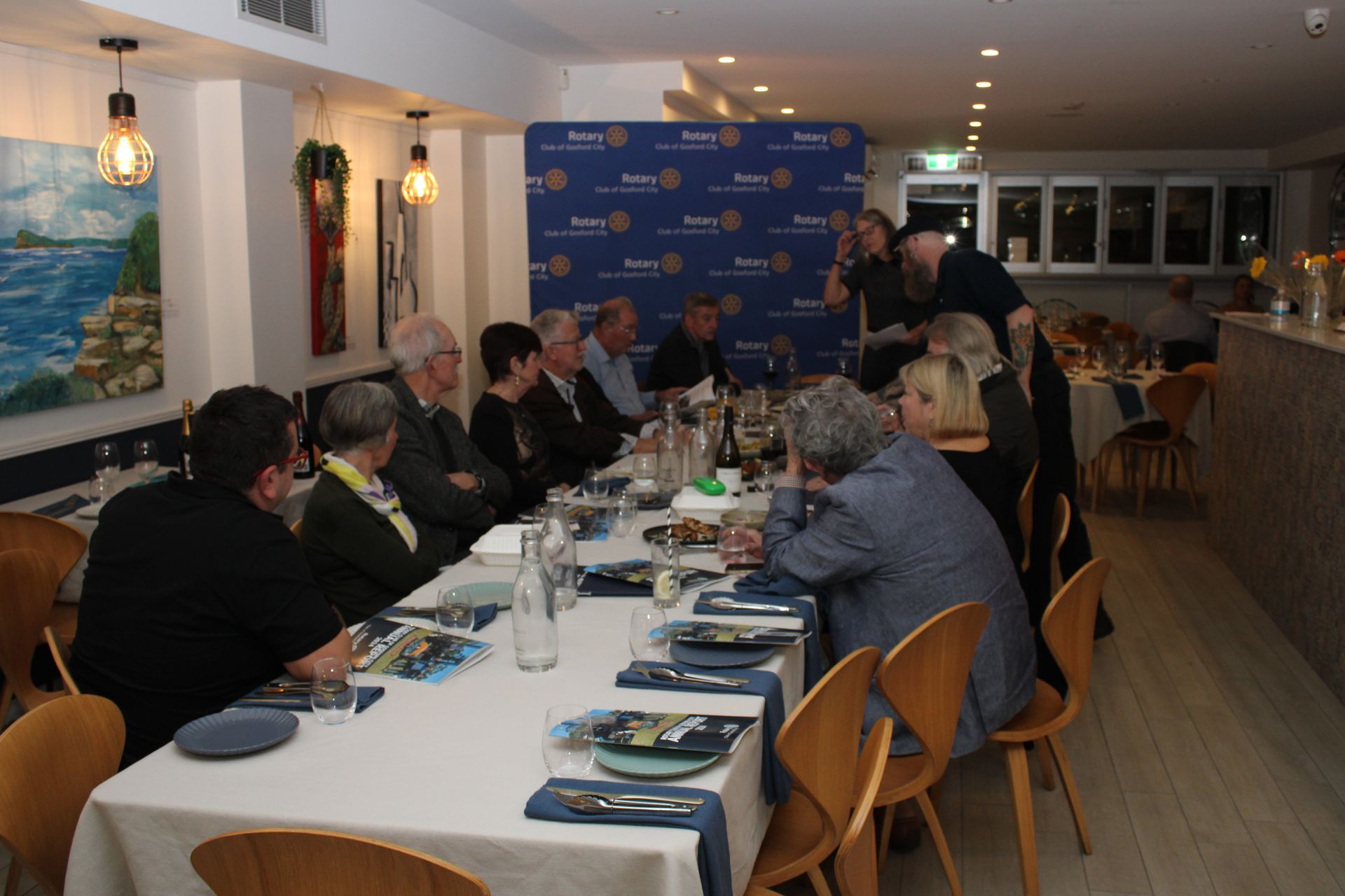 A group of people are sitting at a long table in a restaurant.