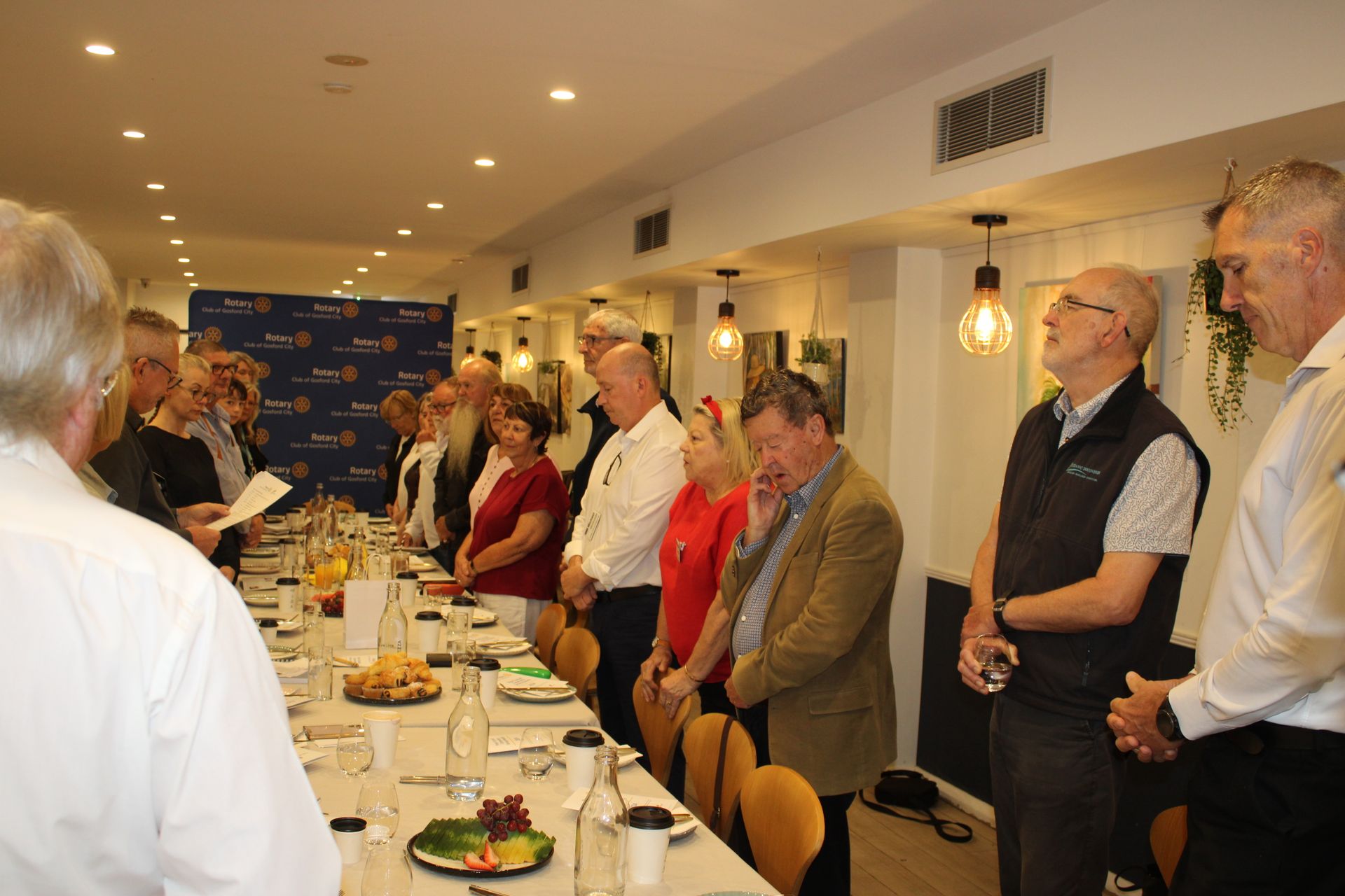A group of people are standing around a long table in a room.