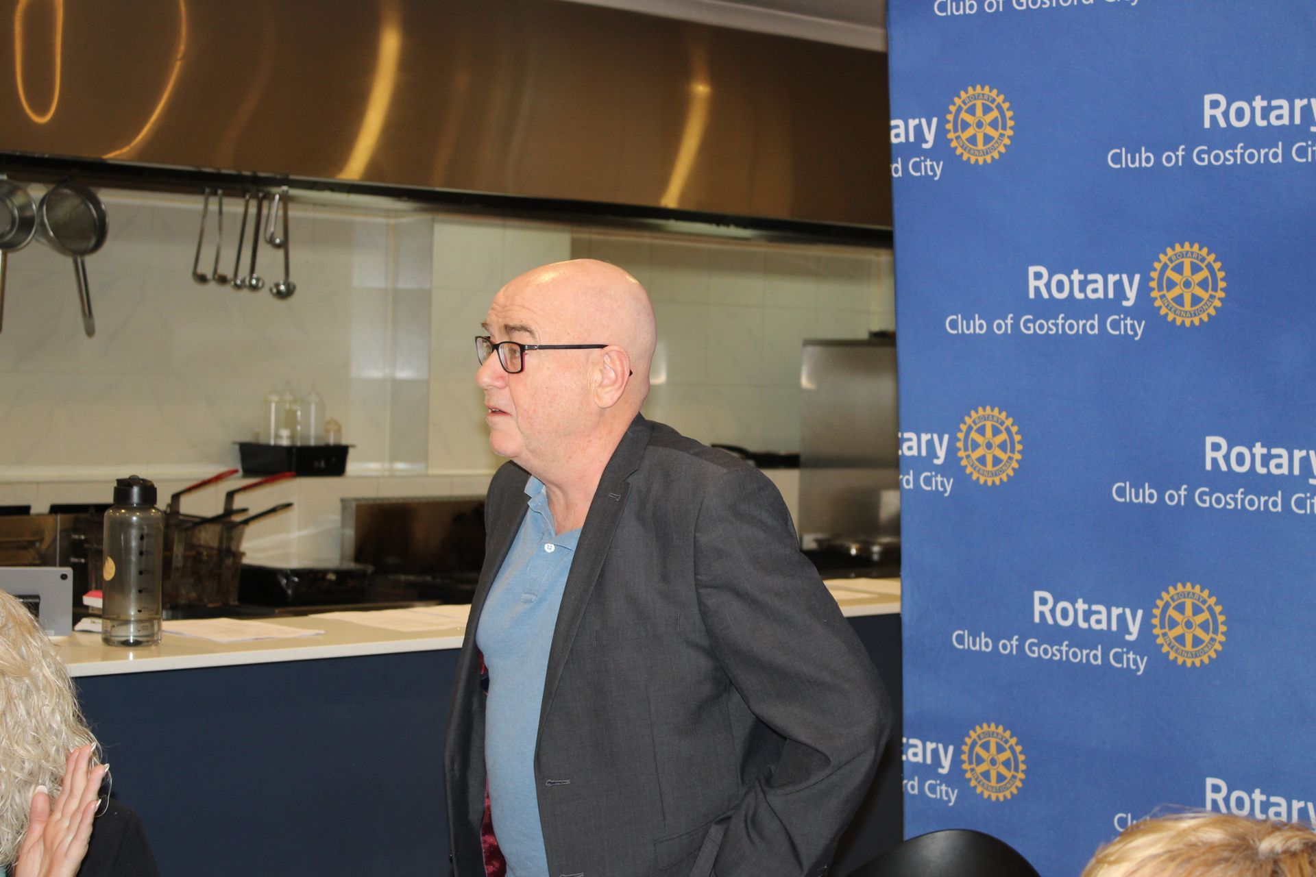 A man is standing in front of a sign that says rotary