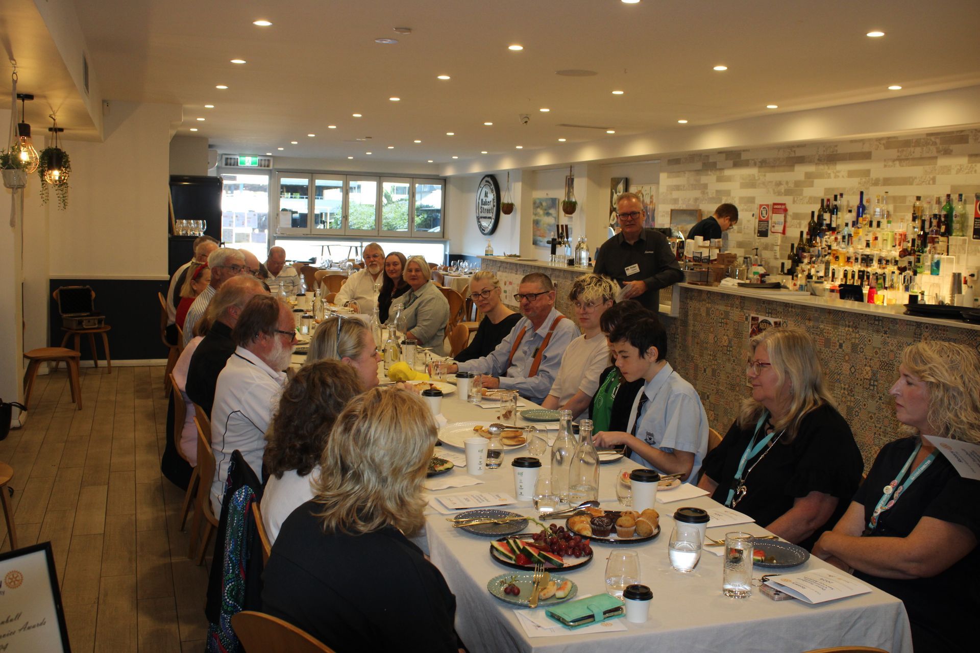 A group of people are sitting at a long table in a restaurant.