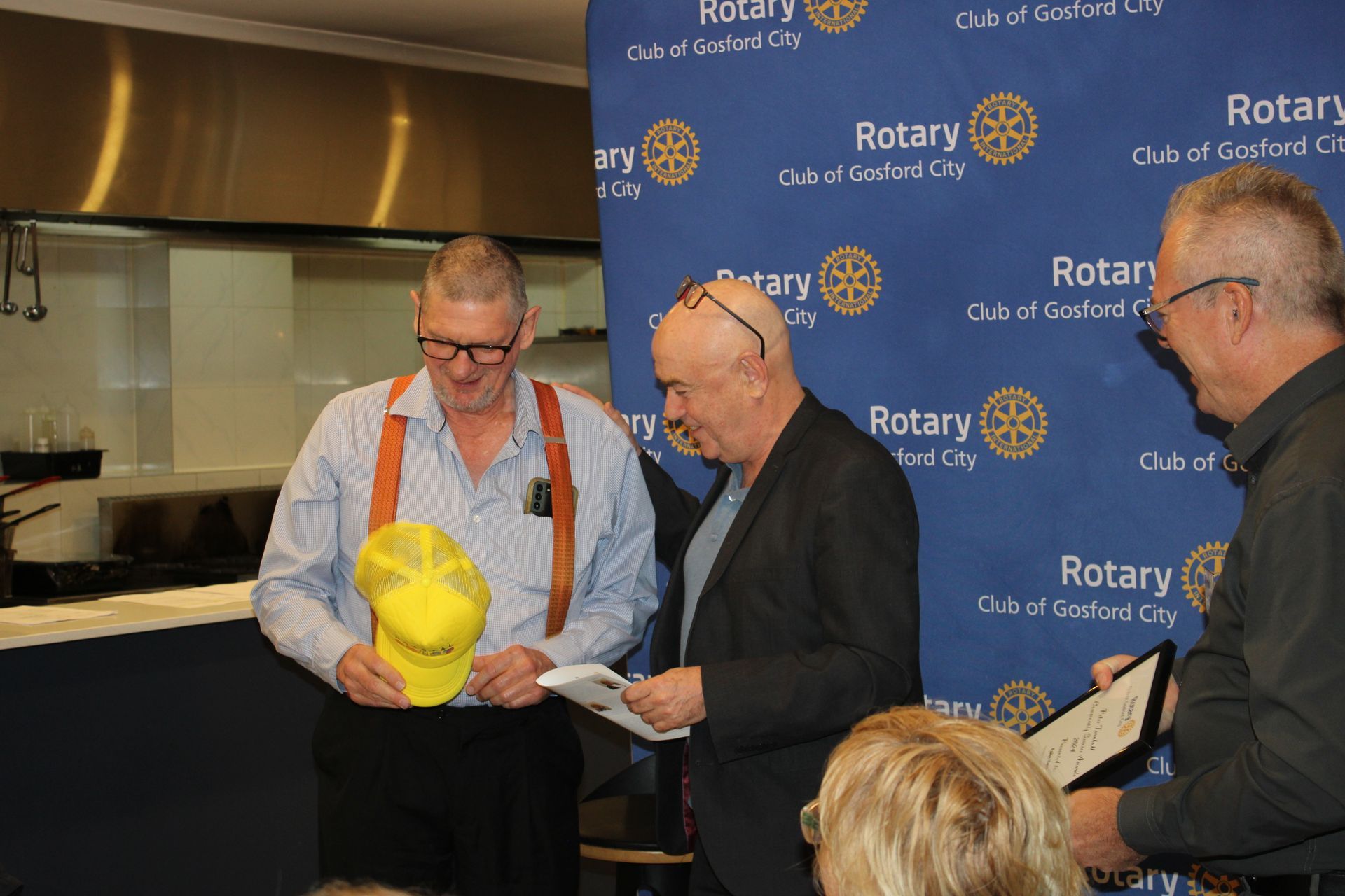 A group of men are standing in front of a rotary sign.
