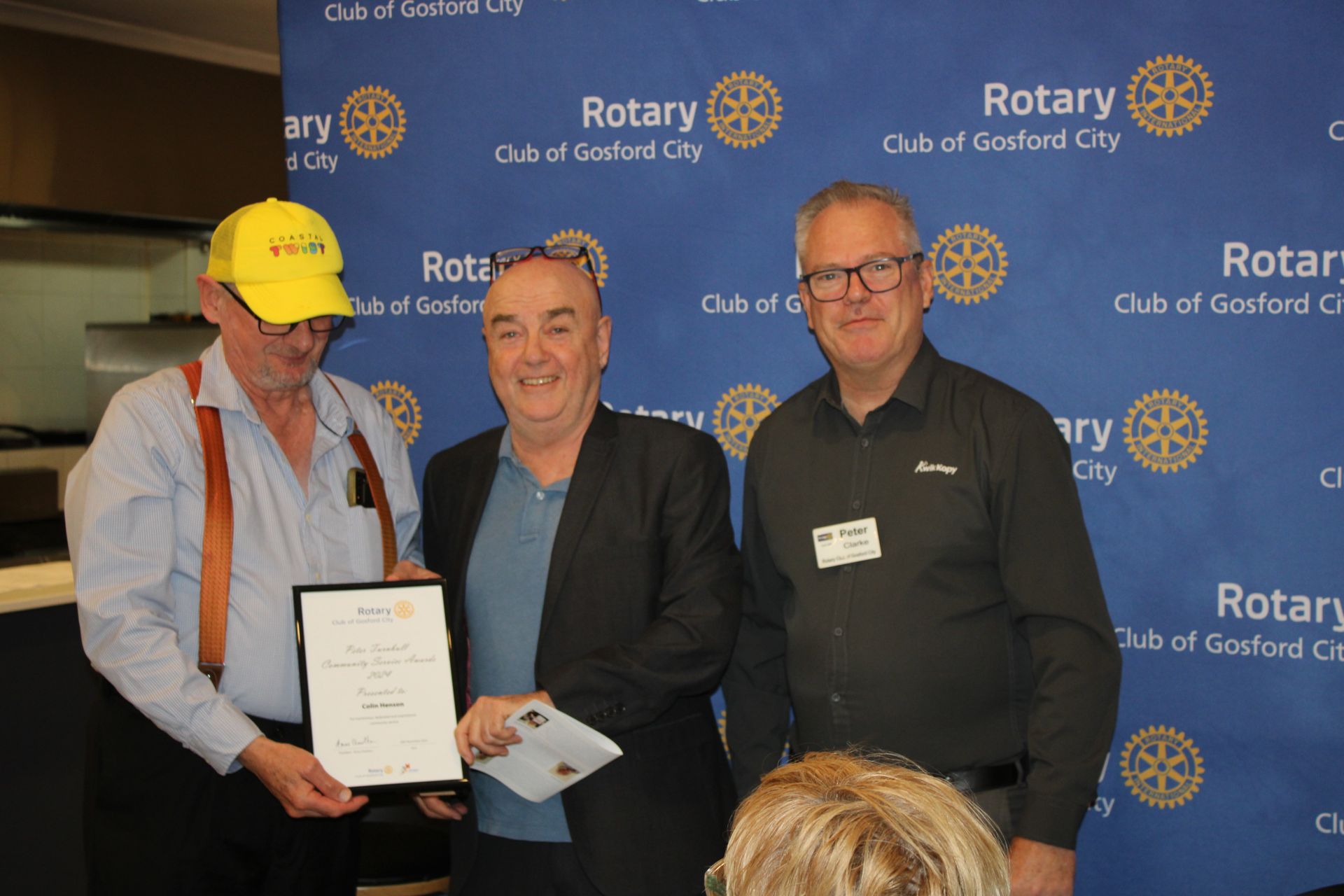A group of men are posing for a picture in front of a rotary sign.