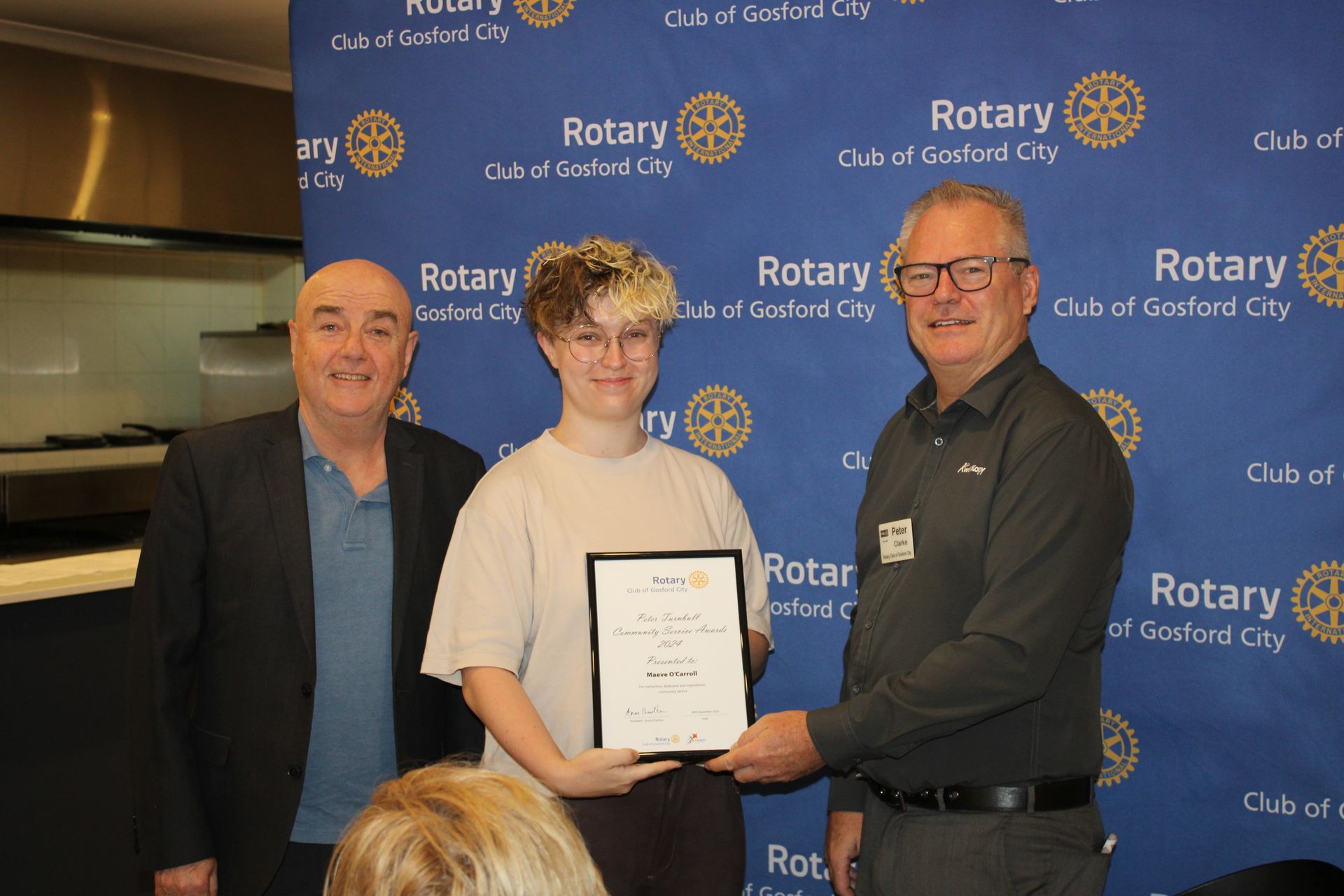 A man is holding a certificate in front of a group of people.