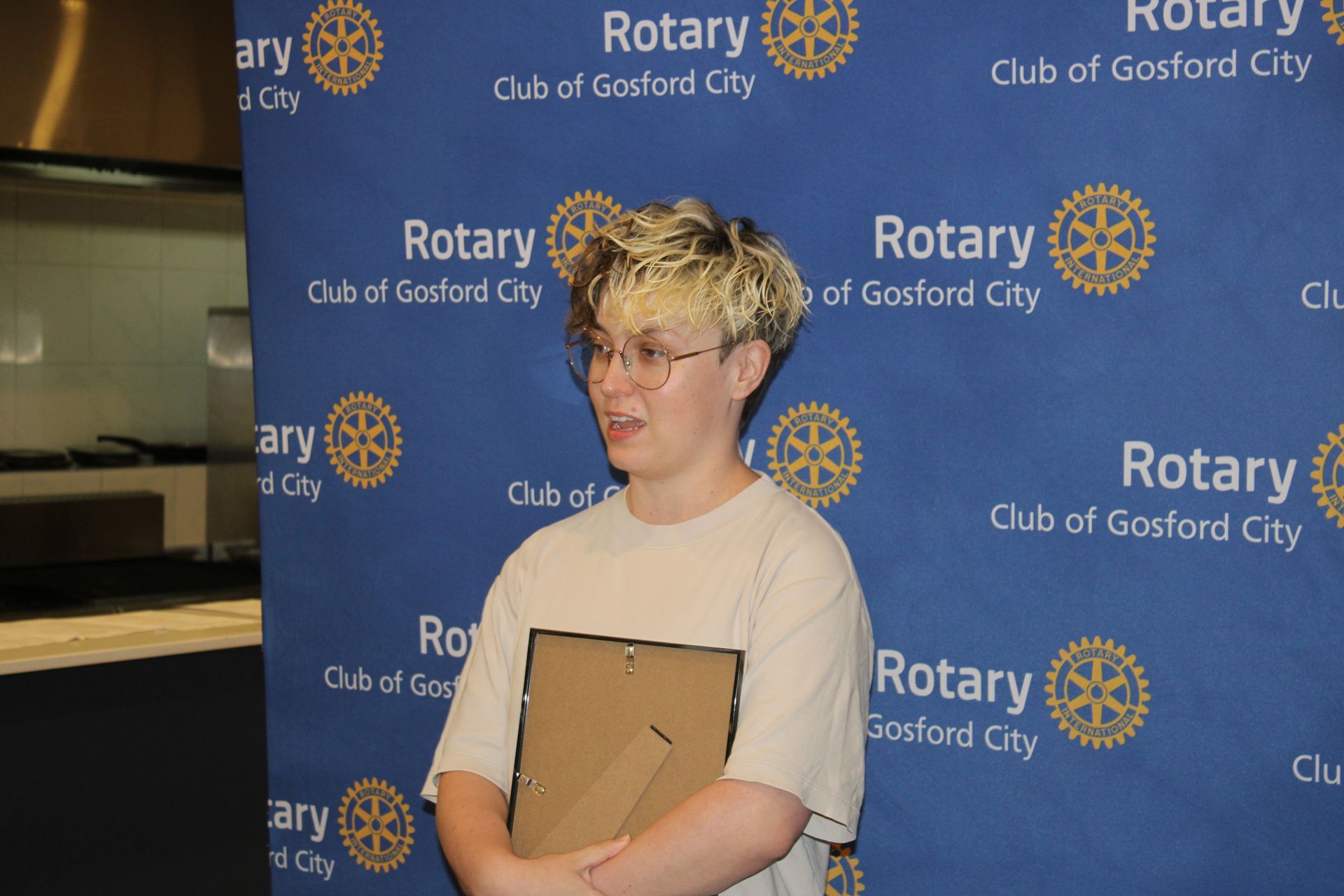 A young man is standing in front of a blue background that says rotary