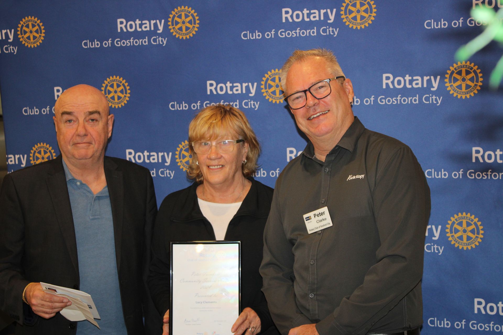 A group of people standing in front of a rotary sign holding a certificate.