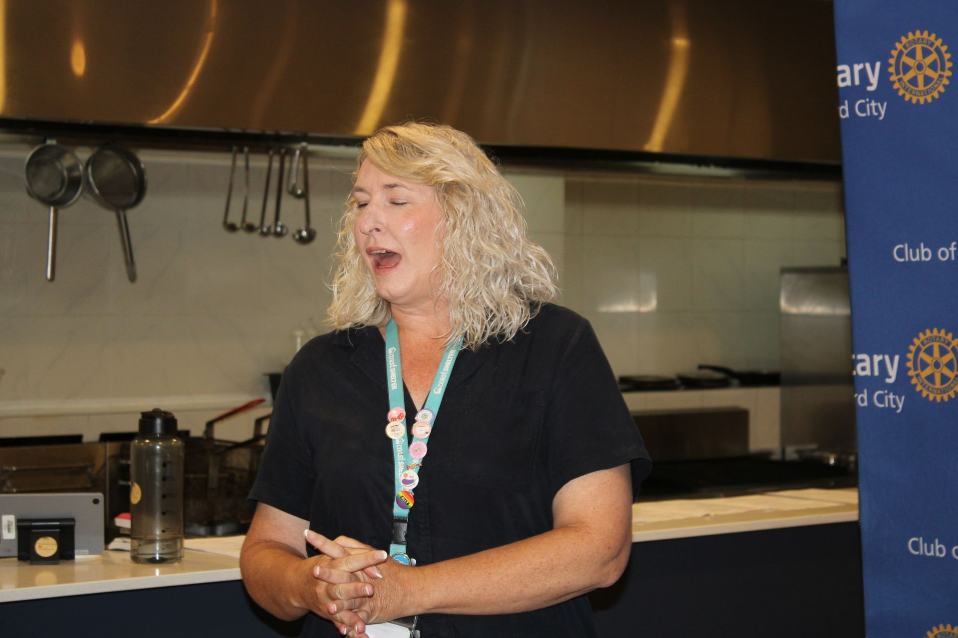 A woman is standing in front of a sign that says rotary