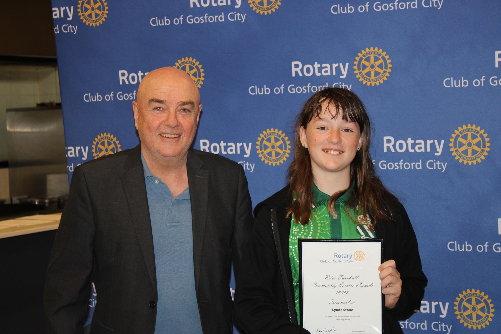 A man and a girl are standing in front of a blue background that says rotary
