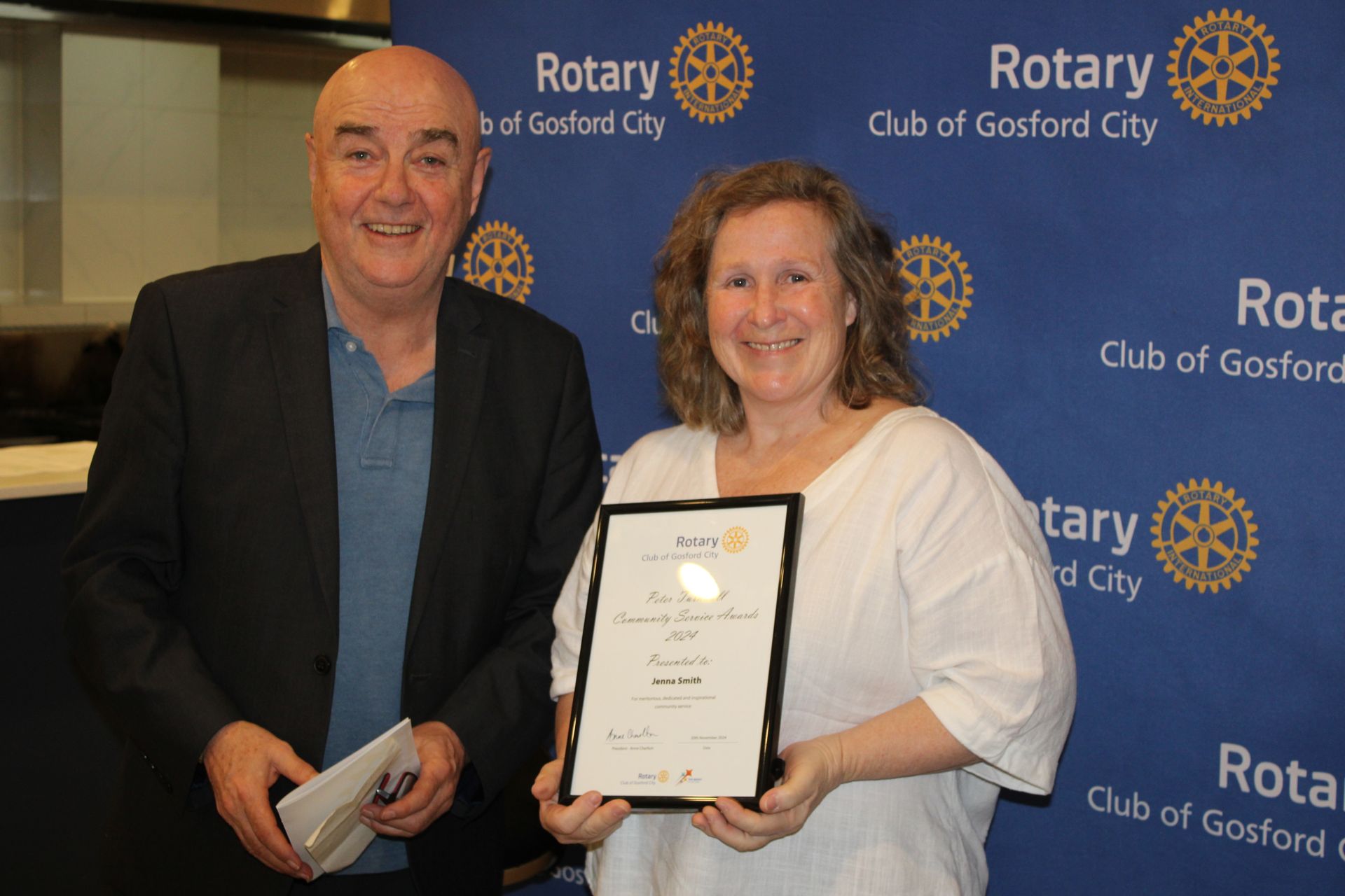 A man and a woman are standing next to each other holding a certificate.