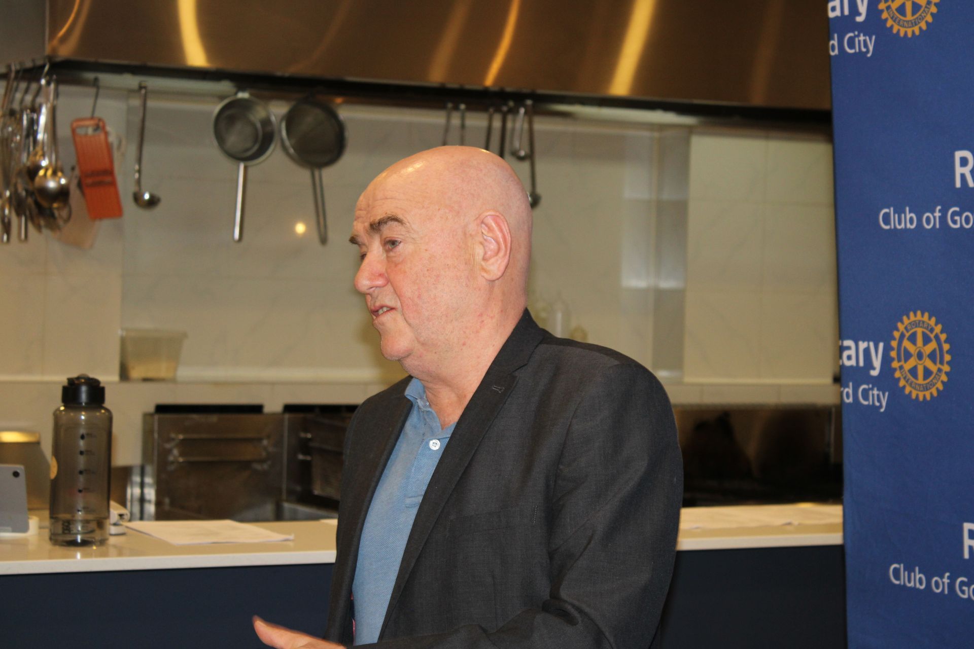 A man in a suit is standing in front of a sign that says rotary