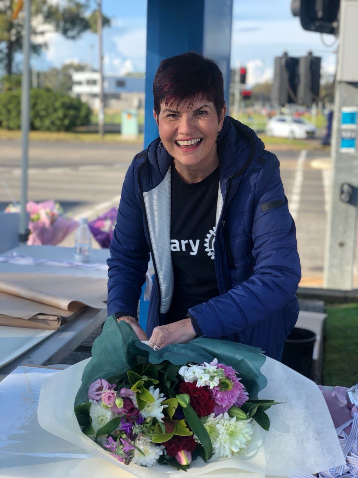 A woman in a blue jacket is holding a bouquet of flowers.
