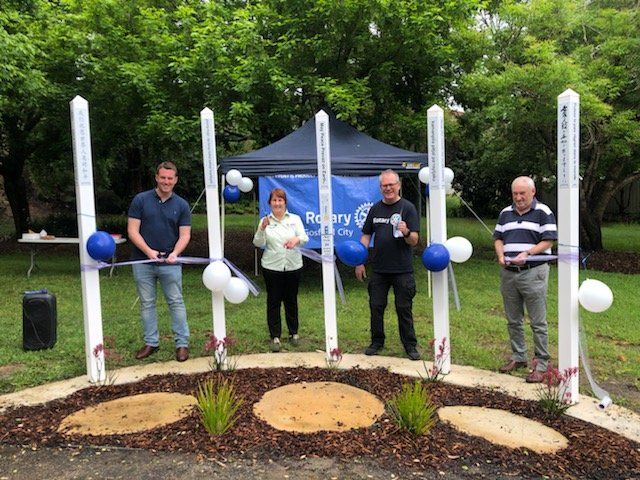 A group of people are standing in a park cutting a ribbon.