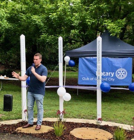 A man stands in front of a sign that says rotary club of oxford city