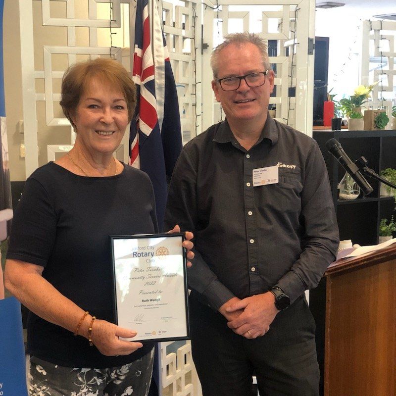 A man and a woman standing next to each other holding a rotary certificate