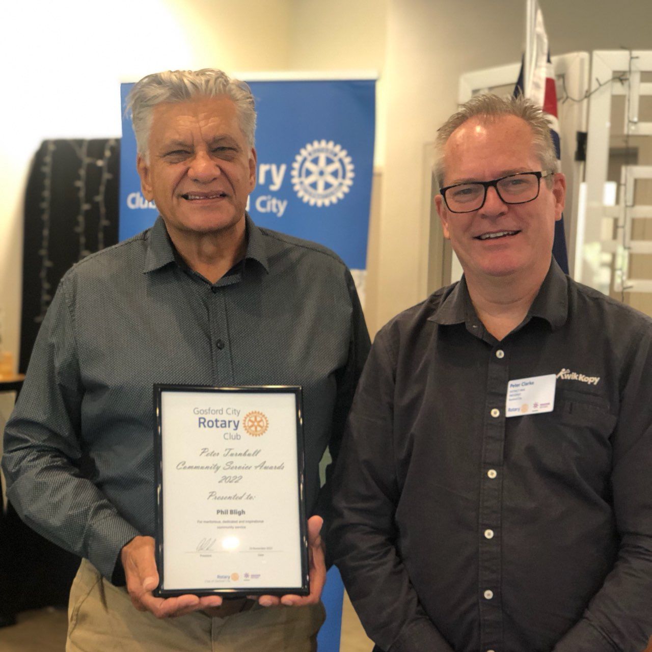 Two men holding a certificate that says rotary on it