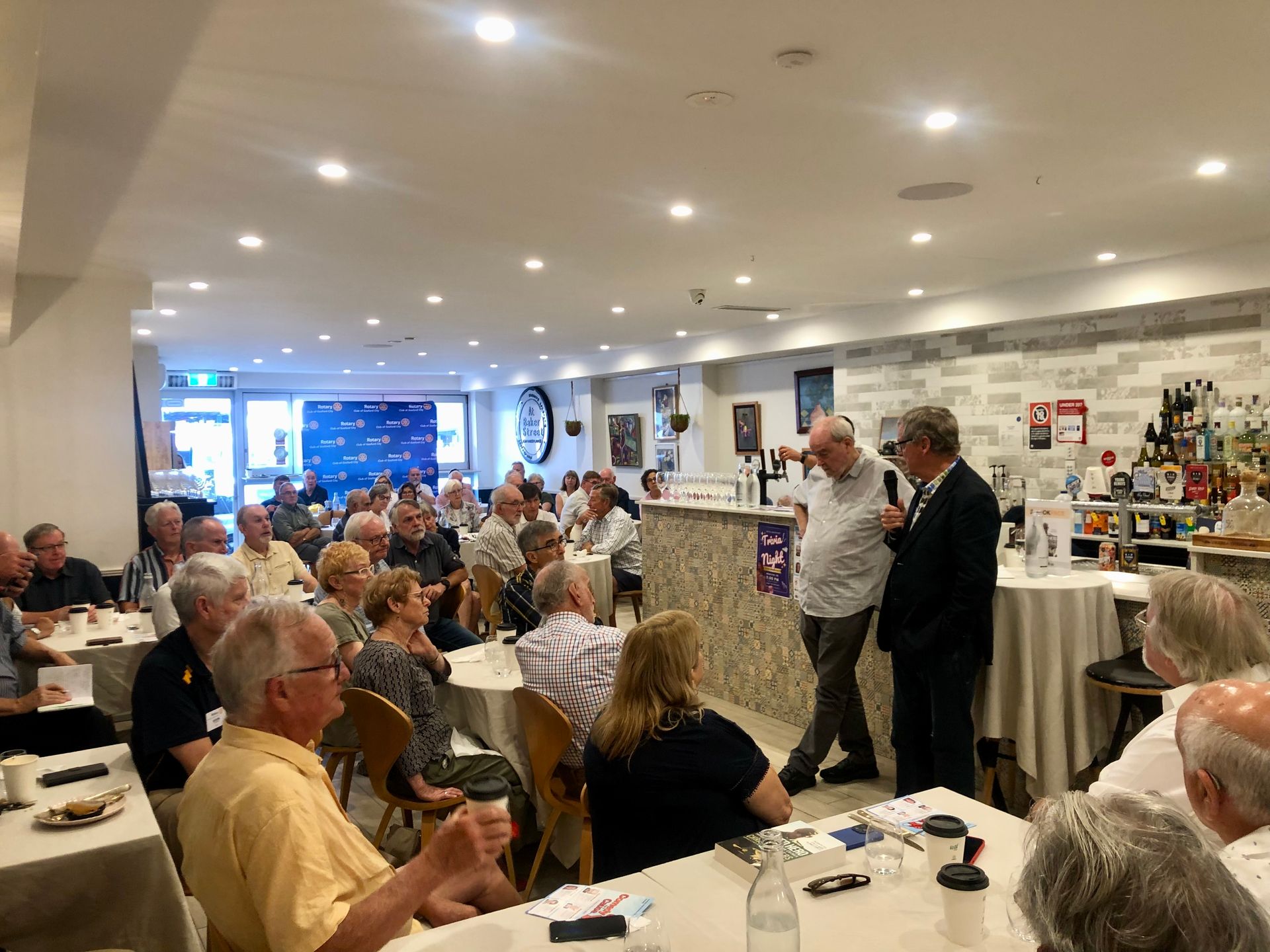 A group of people are sitting at tables in a restaurant.