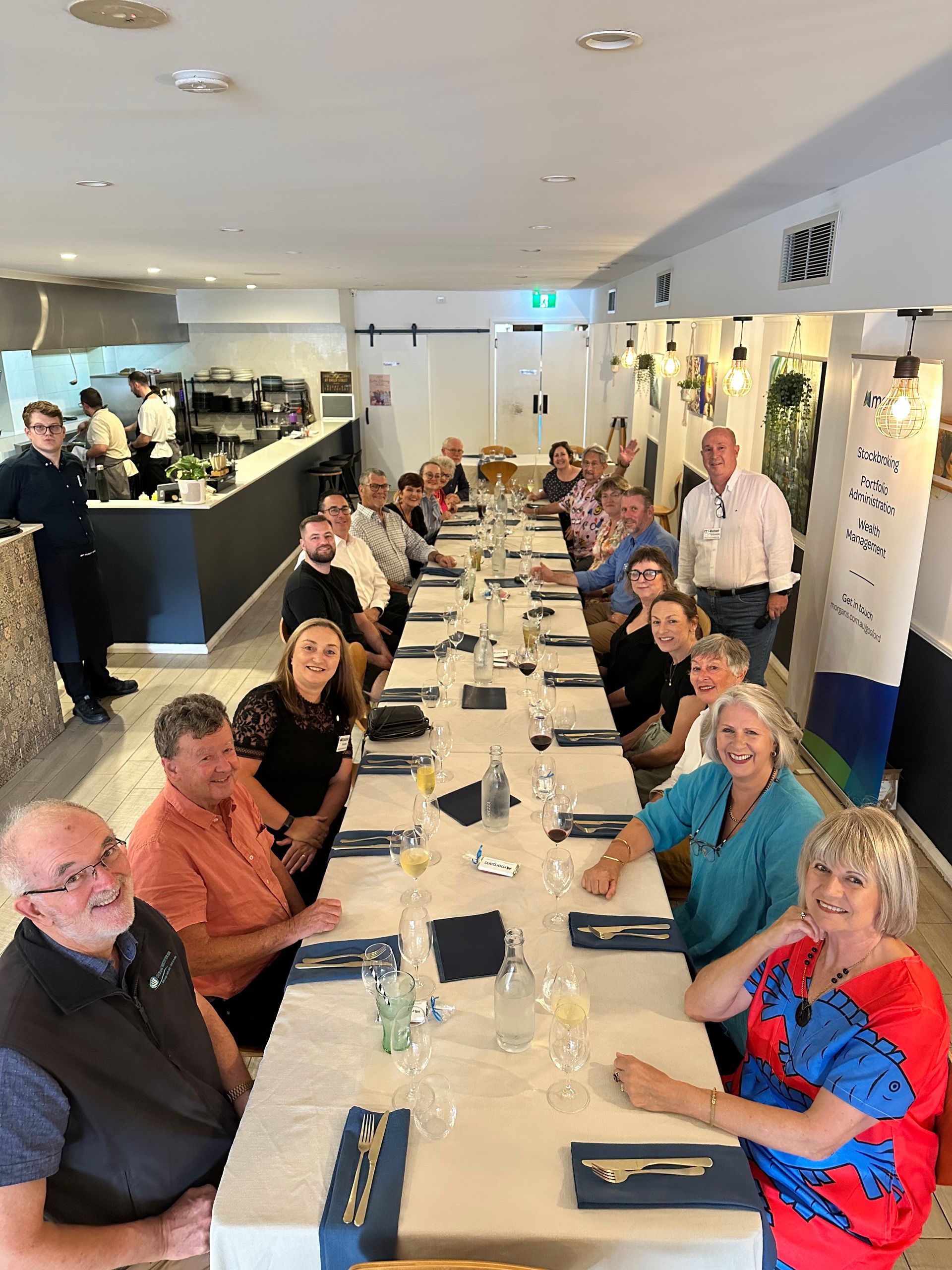 A group of people are sitting at long tables in a restaurant.
