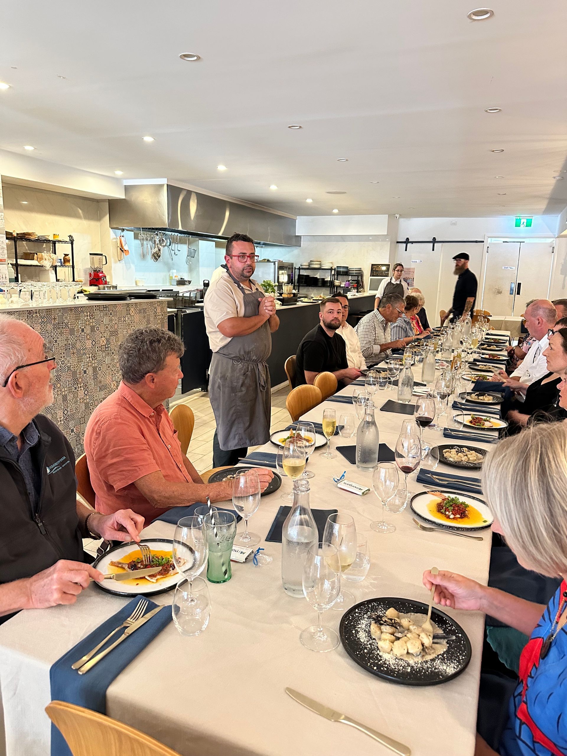 A group of people are sitting at tables in a restaurant eating food.
