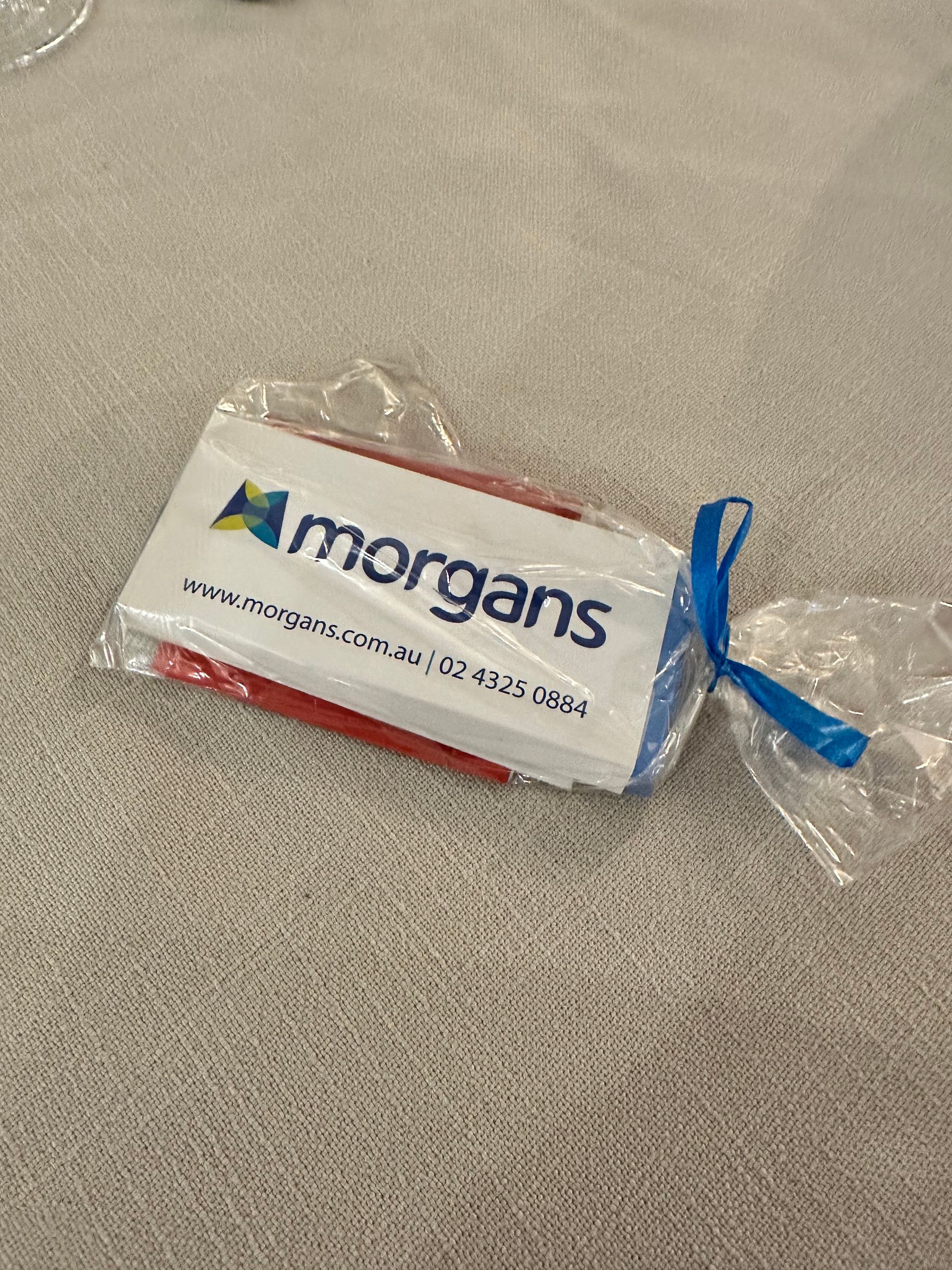 A morgans candy bar is wrapped in plastic and tied with a blue ribbon.