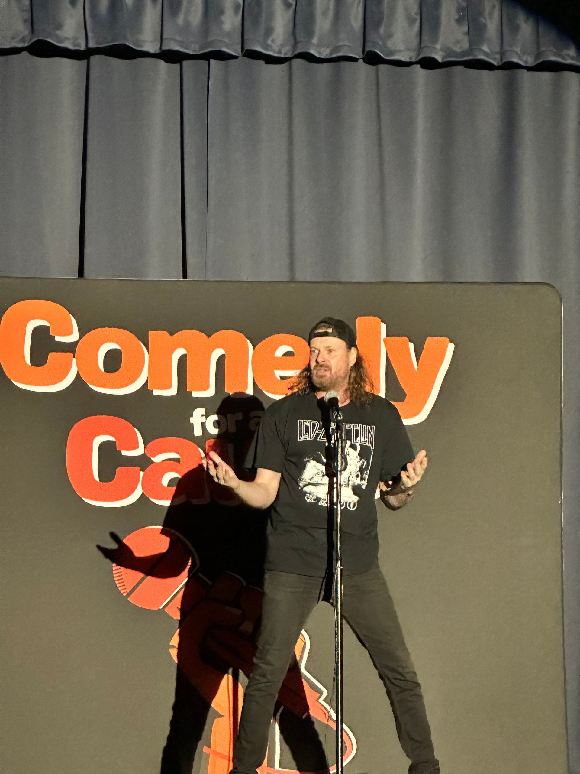 A man is standing in front of a sign that says comedy