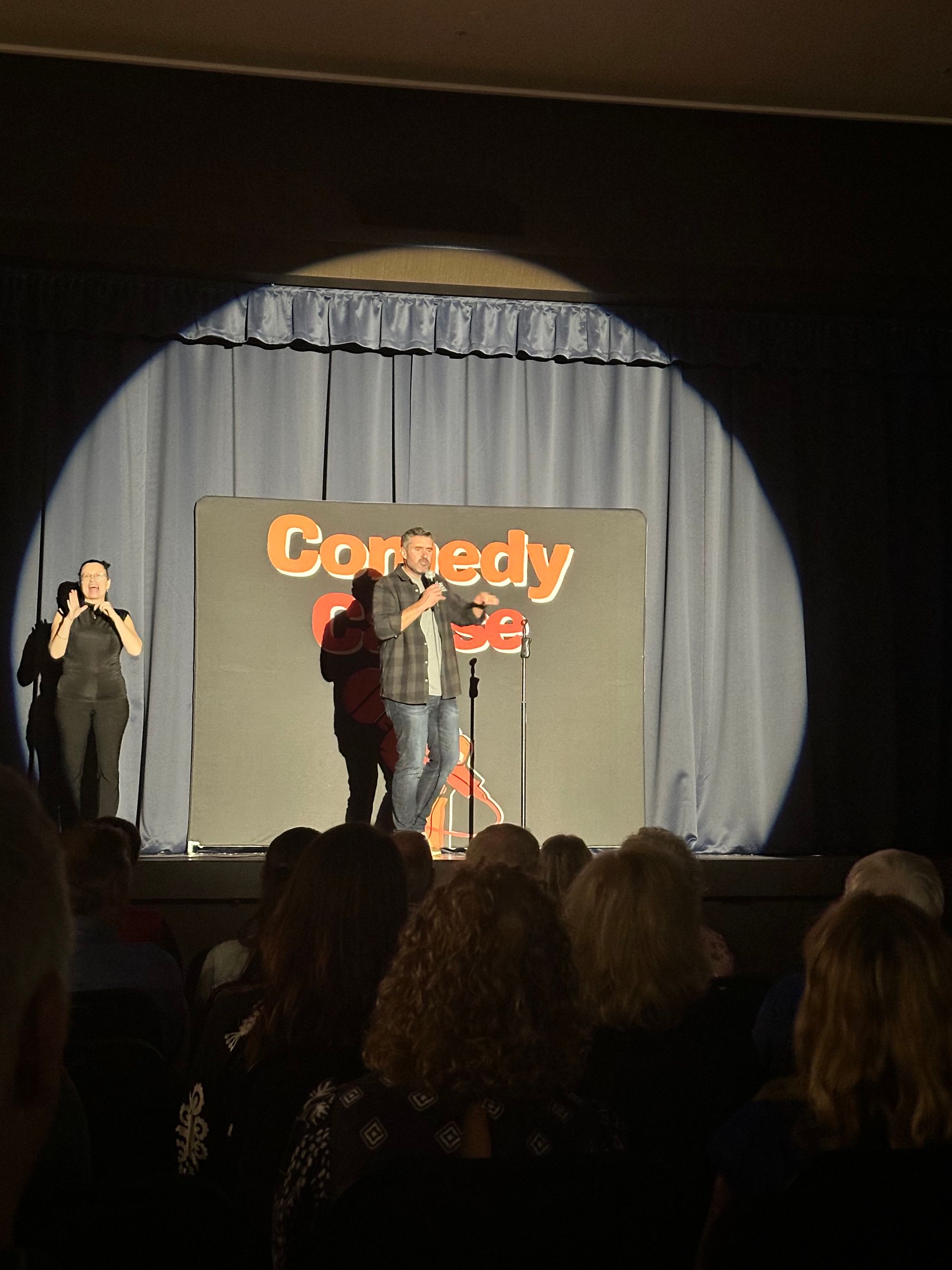 A group of people standing on a stage in front of a sign that says comedy