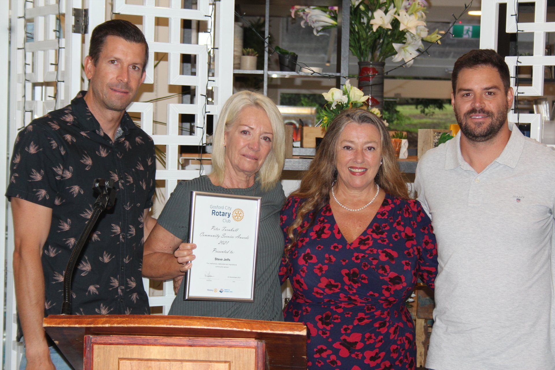 A group of people standing around a podium holding a certificate.