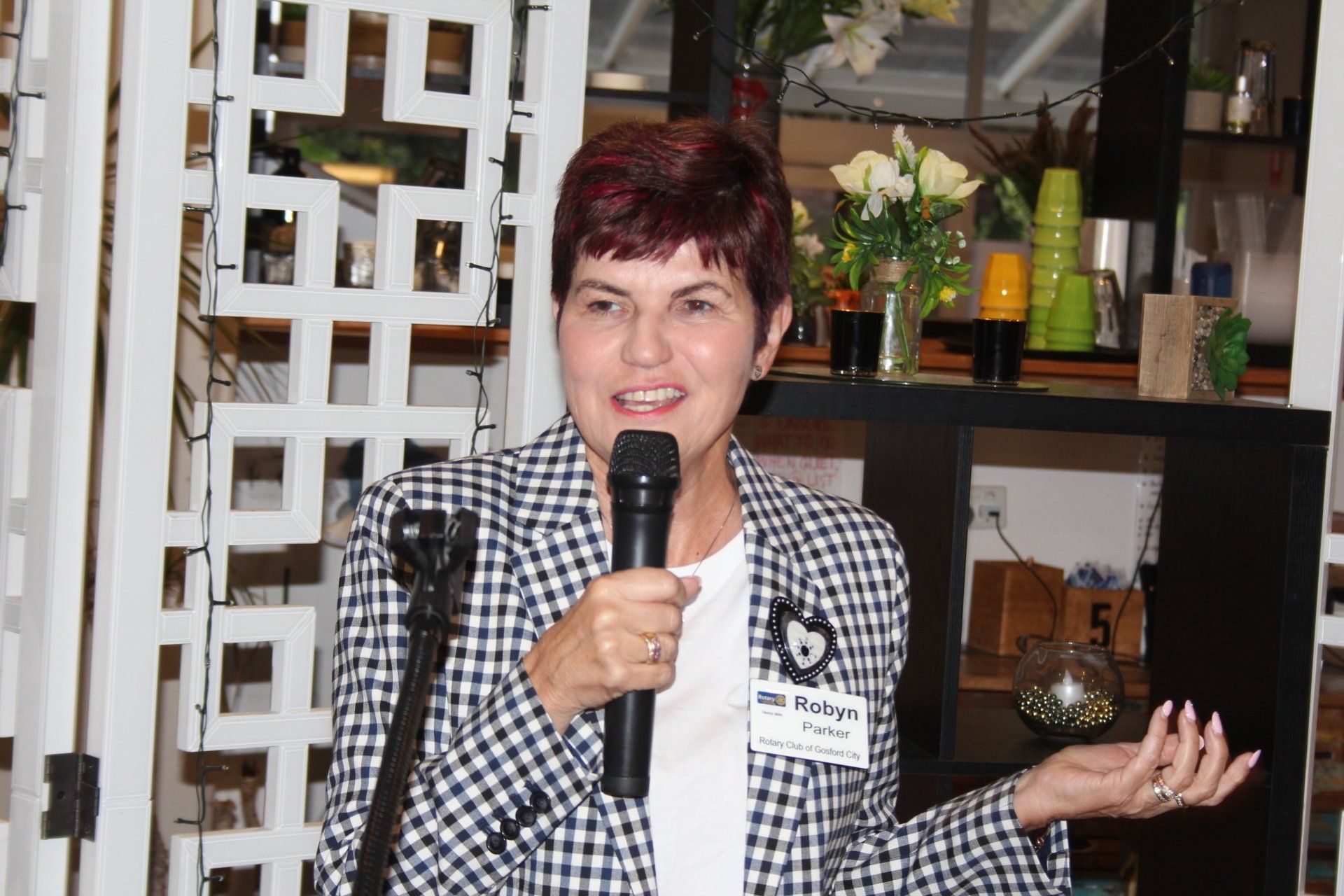 A woman in a plaid jacket is holding a microphone