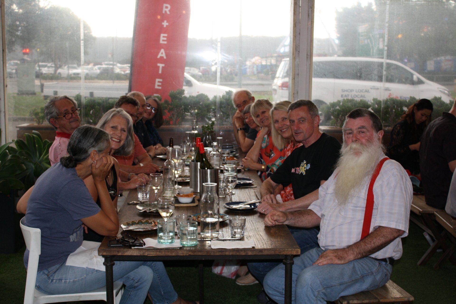 A group of people are sitting at a long table in front of a sign that says r + eate