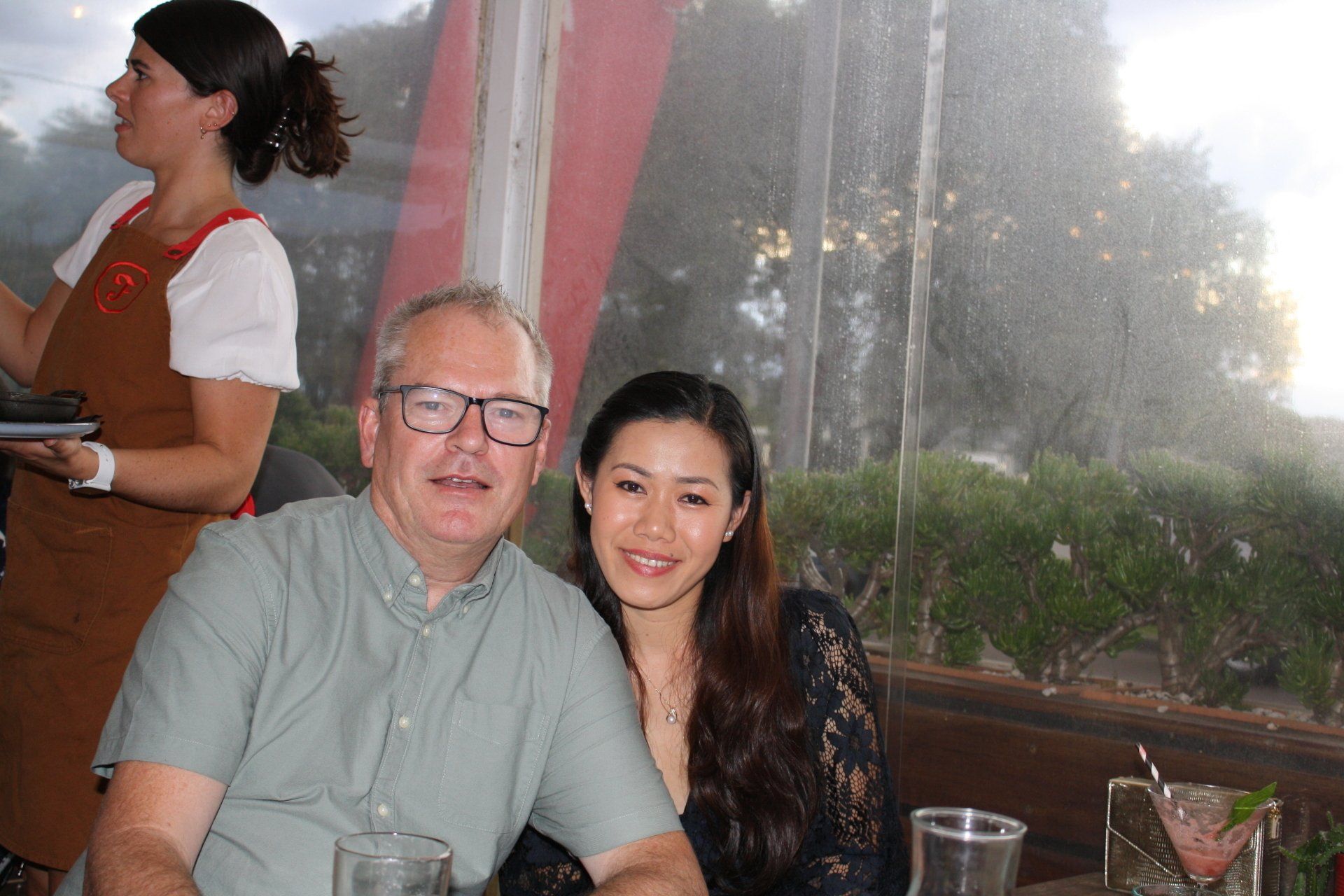 A man and a woman are posing for a picture in a restaurant.
