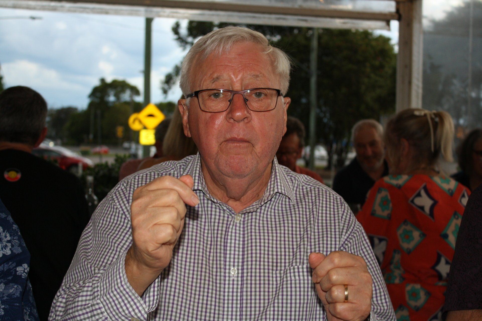 A man wearing glasses and a plaid shirt is sitting in front of a window.