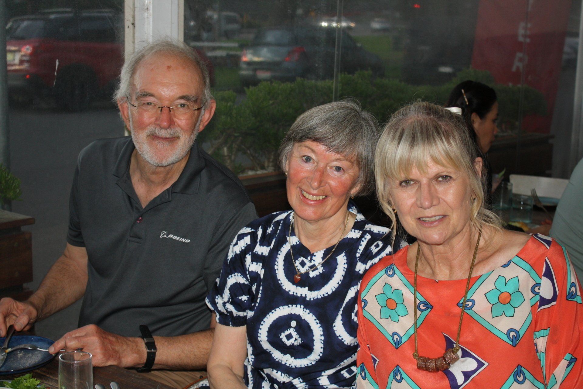 A man and two women are posing for a picture while sitting at a table.