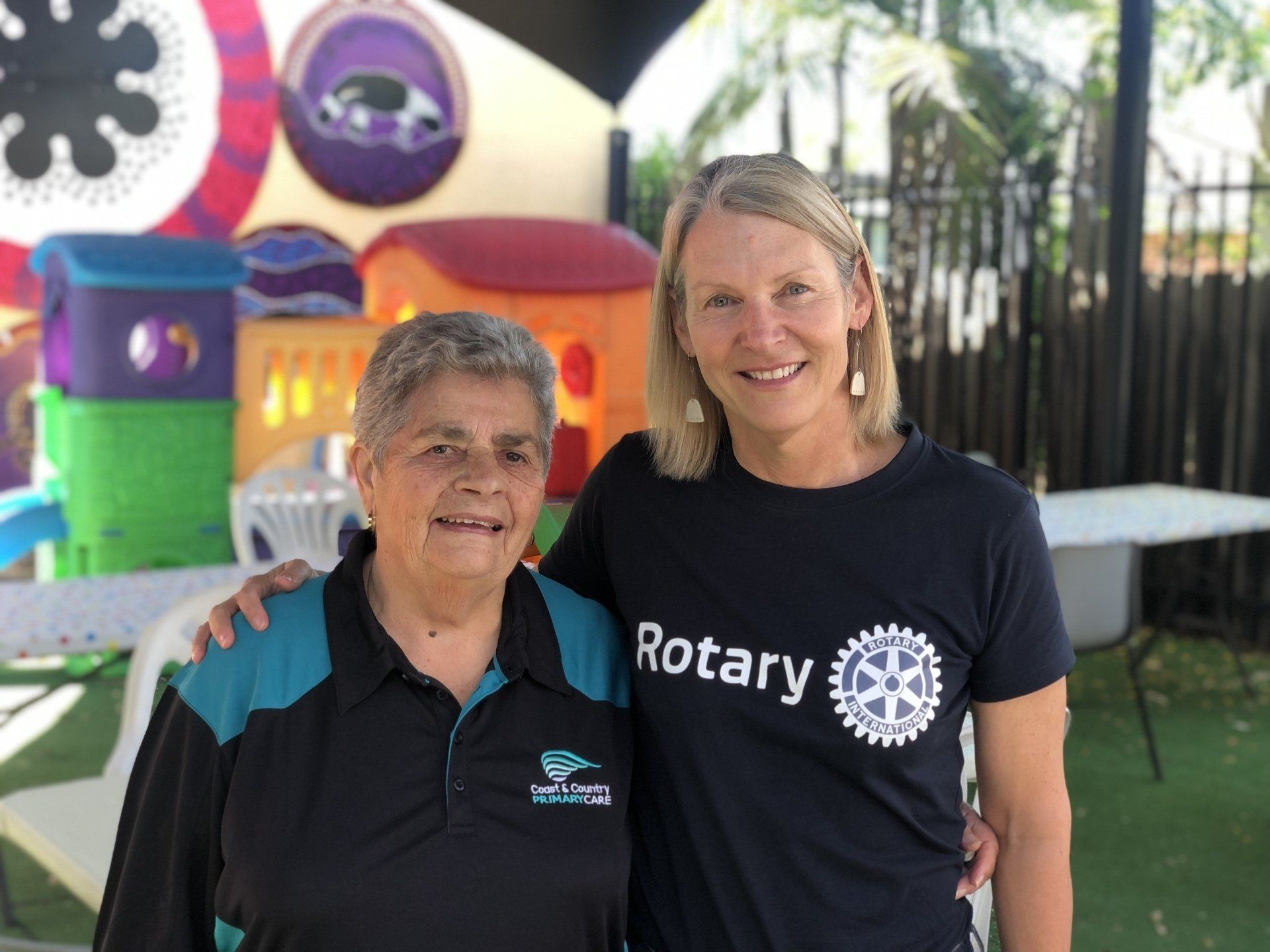 Two women are posing for a picture and one of them is wearing a rotary shirt.