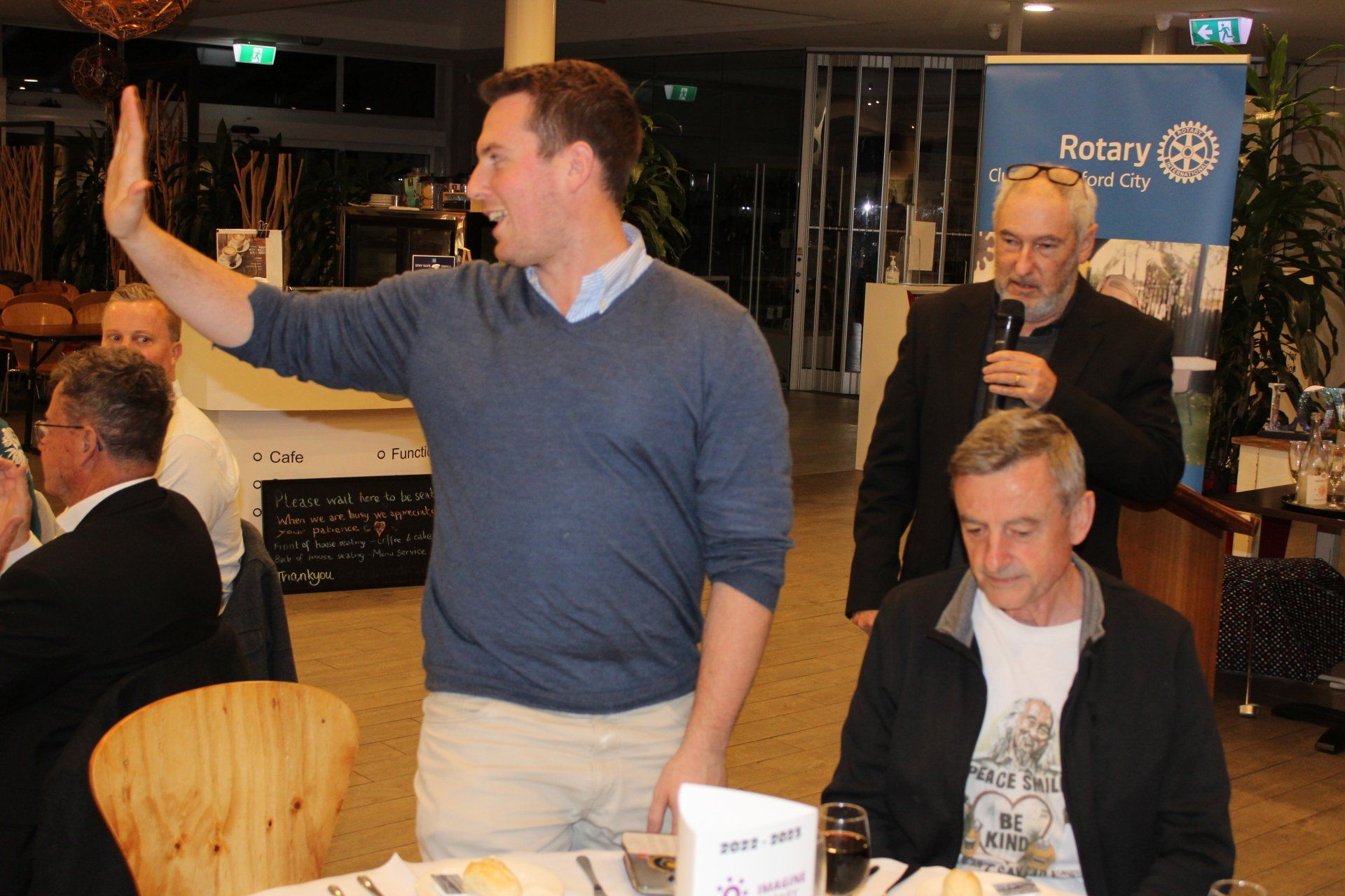 A man giving a high five in front of a rotary sign