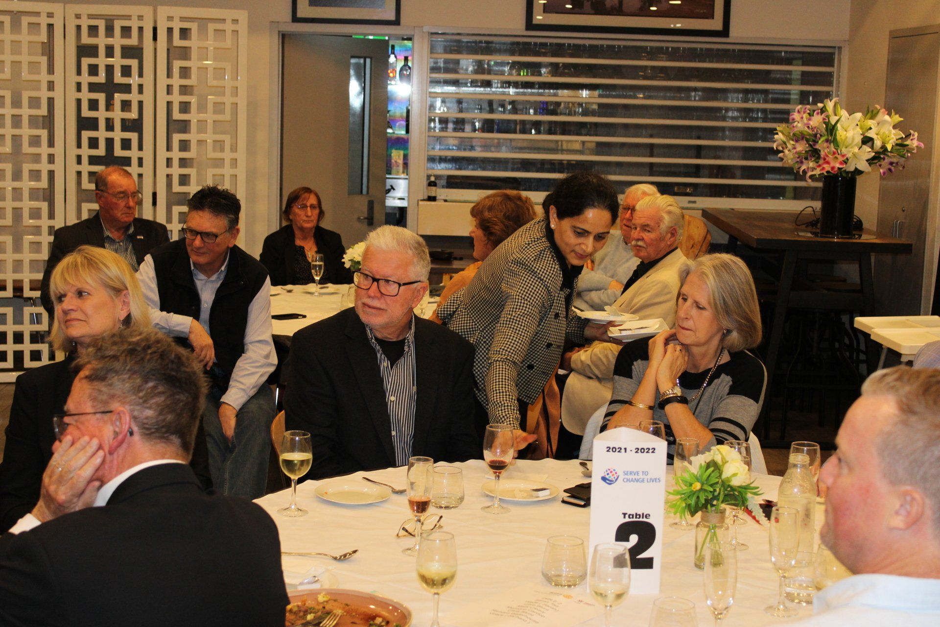 A group of people are sitting at a table with a number 2 on it