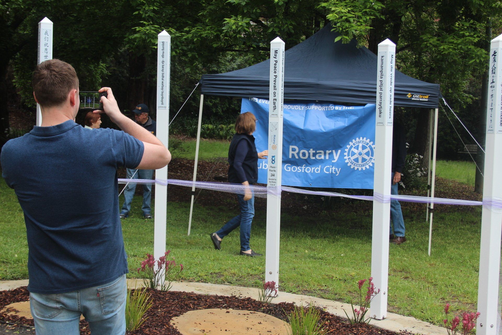 A man is taking a picture of people in front of a banner that says rotary