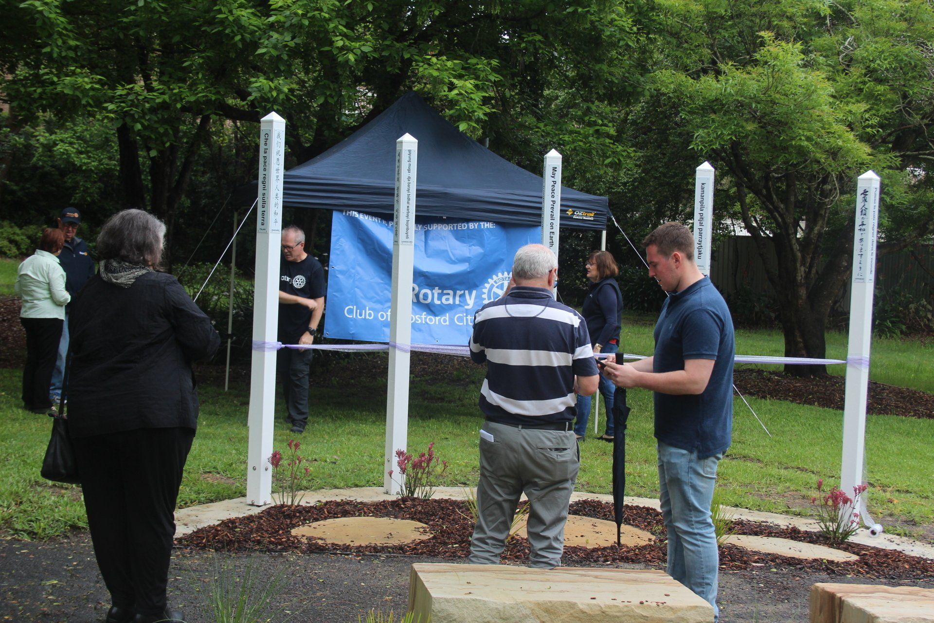 A group of people standing in front of a sign that says rotary
