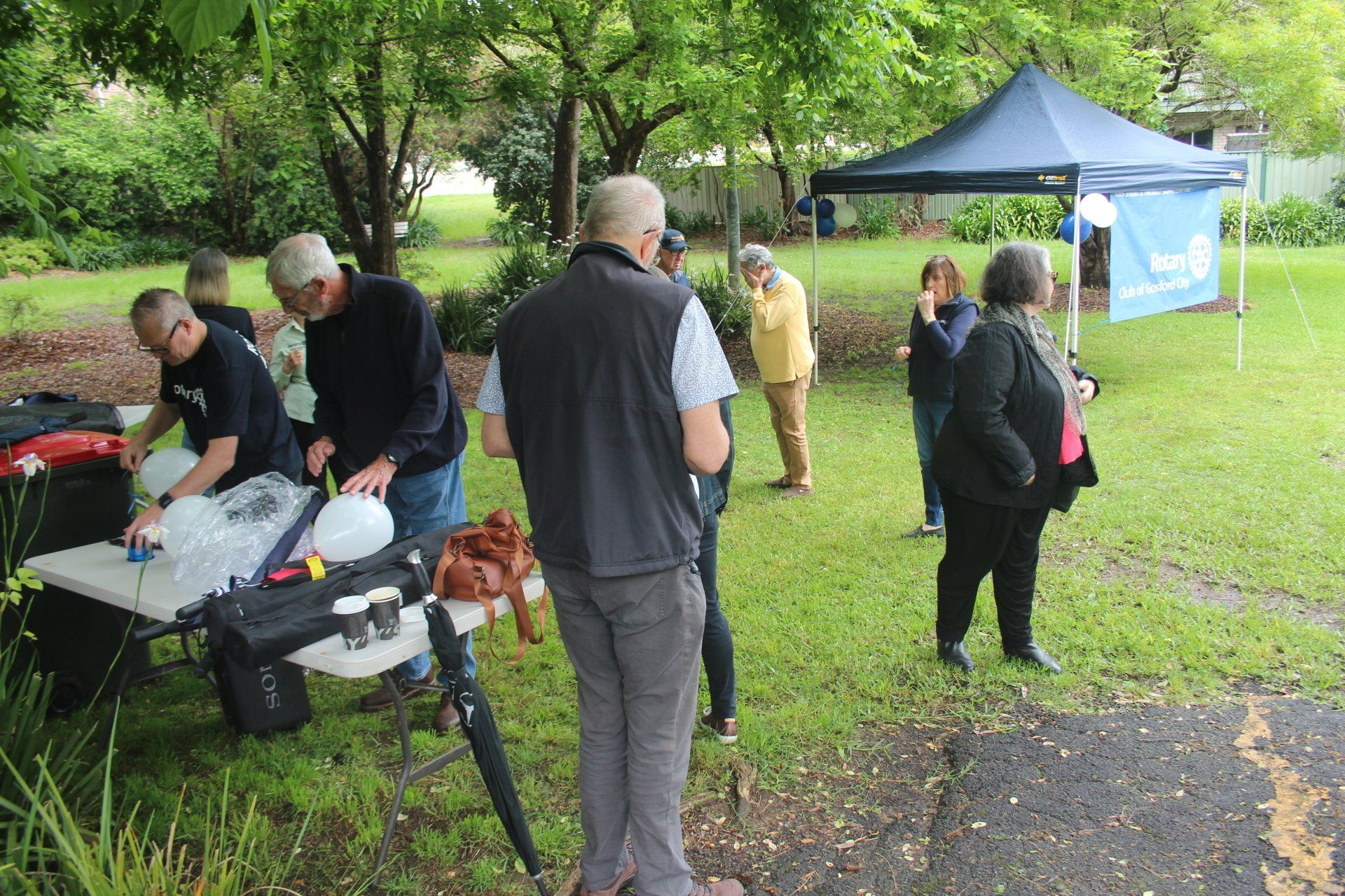 A group of people are standing around a table in a park.