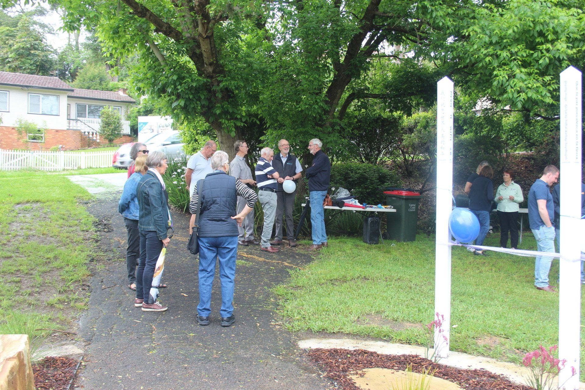 A group of people are standing in a park talking to each other.