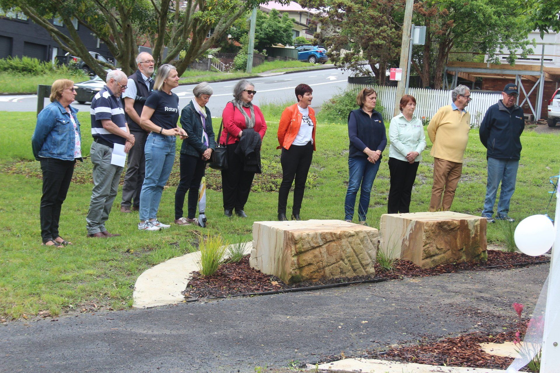A group of people are standing in a grassy area.