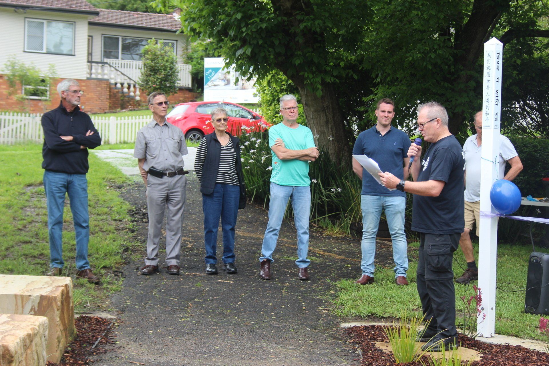 A man is giving a speech to a group of people in a park.