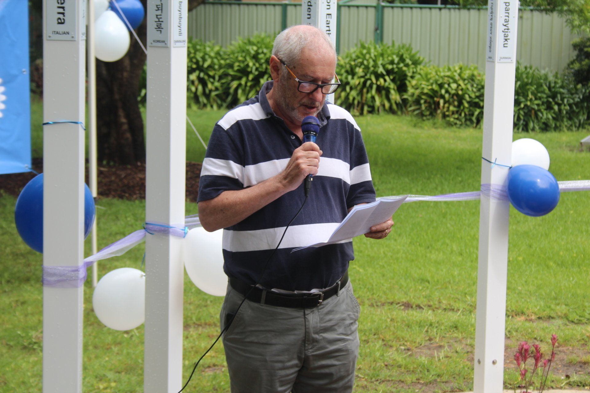 A man speaking into a microphone while holding a piece of paper